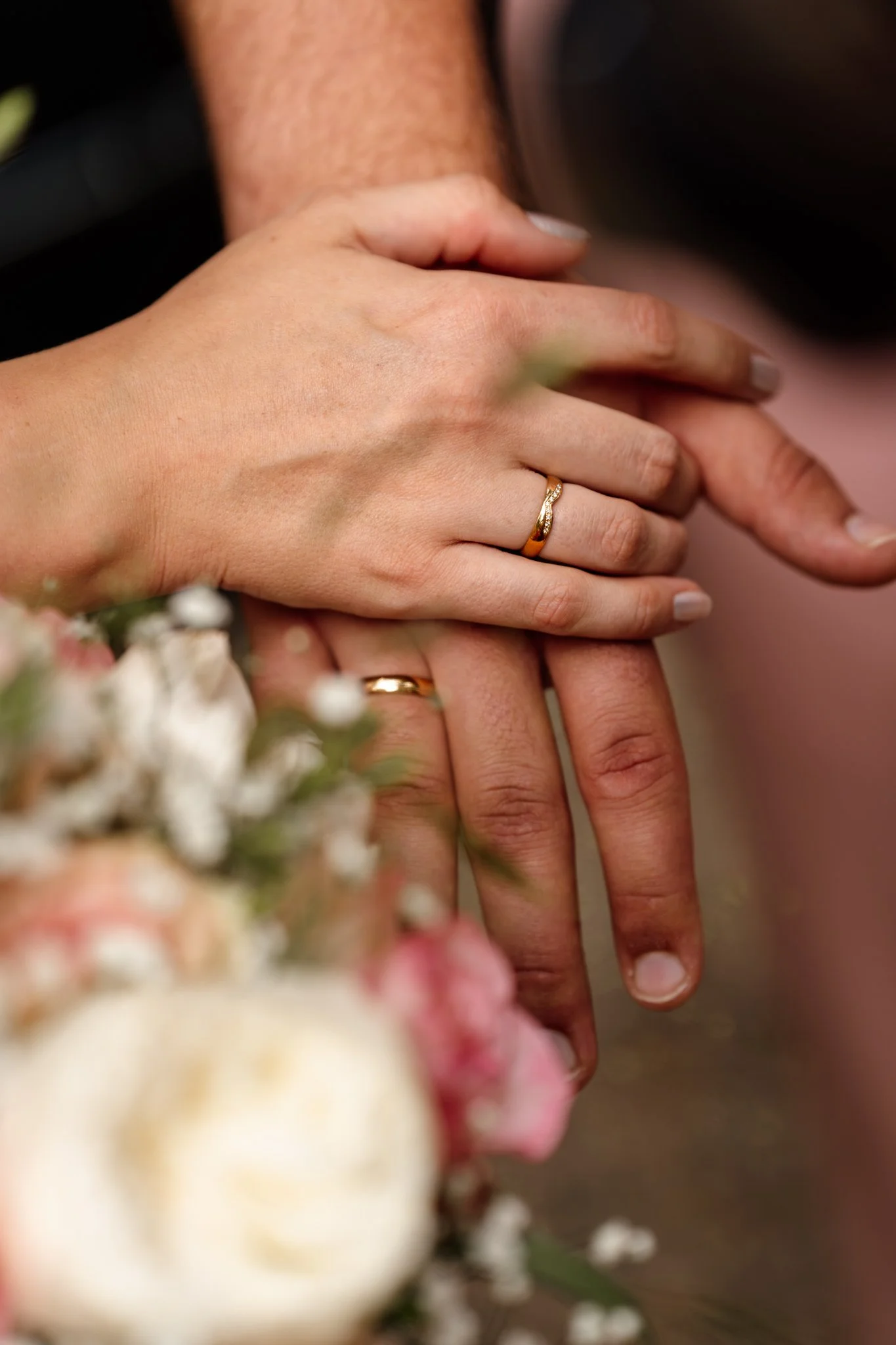 Twee handen met trouwringen, een bruid en een bruidegom, samen op een huwelijksfeest.