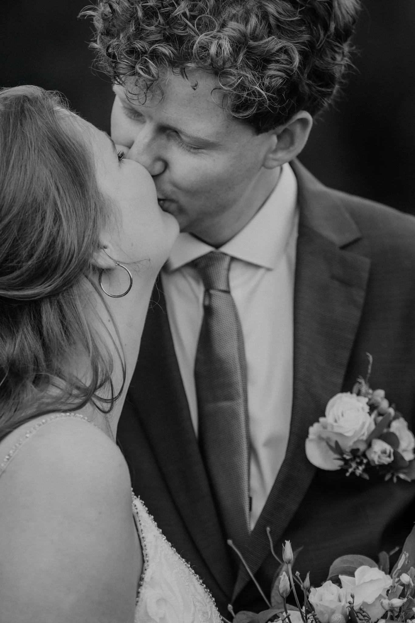 Twee mensen, een bruid en een bruidegom, kussen elkaar op een huwelijksfeest of bruiloft, zwart-wit foto.