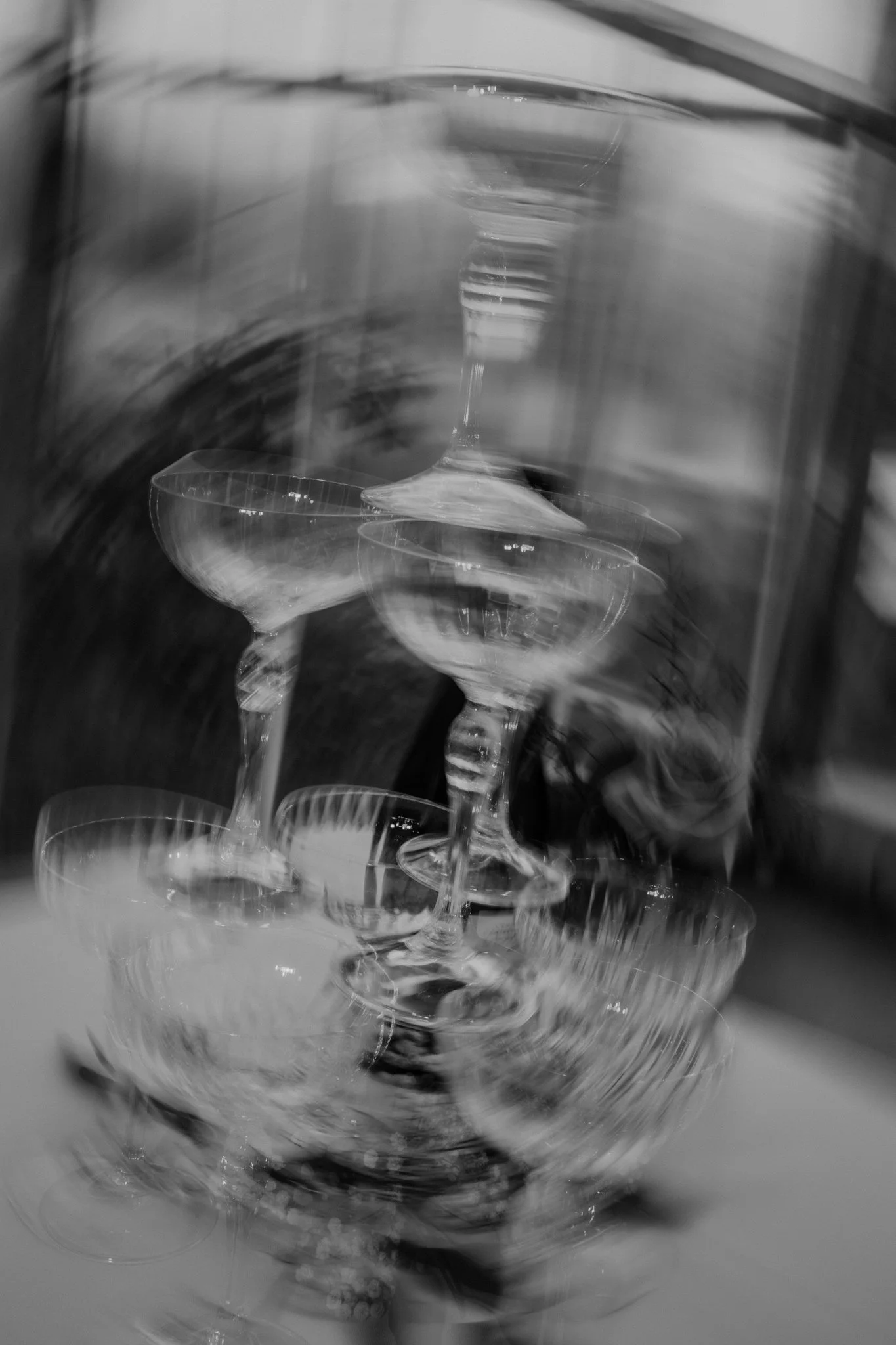 Zes champagneglazen gestapeld op elkaar, met een wazig en vervaagd effect in zwart-wit.