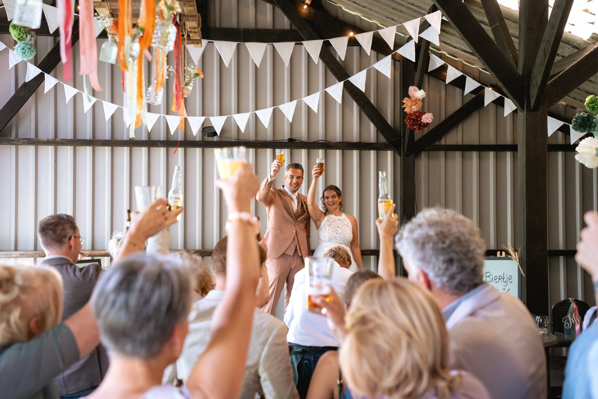 Een trouwfeest met gasten die herinneringen maken en het bruidspaar dat proost met drankjes.