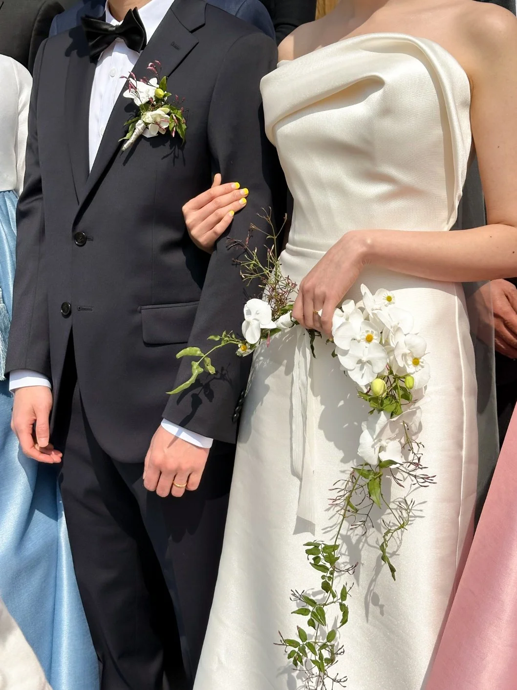 Close-up of a bride and groom at a wedding, with the bride holding a floral bouquet and the groom wearing a dark suit with a boutonniere.