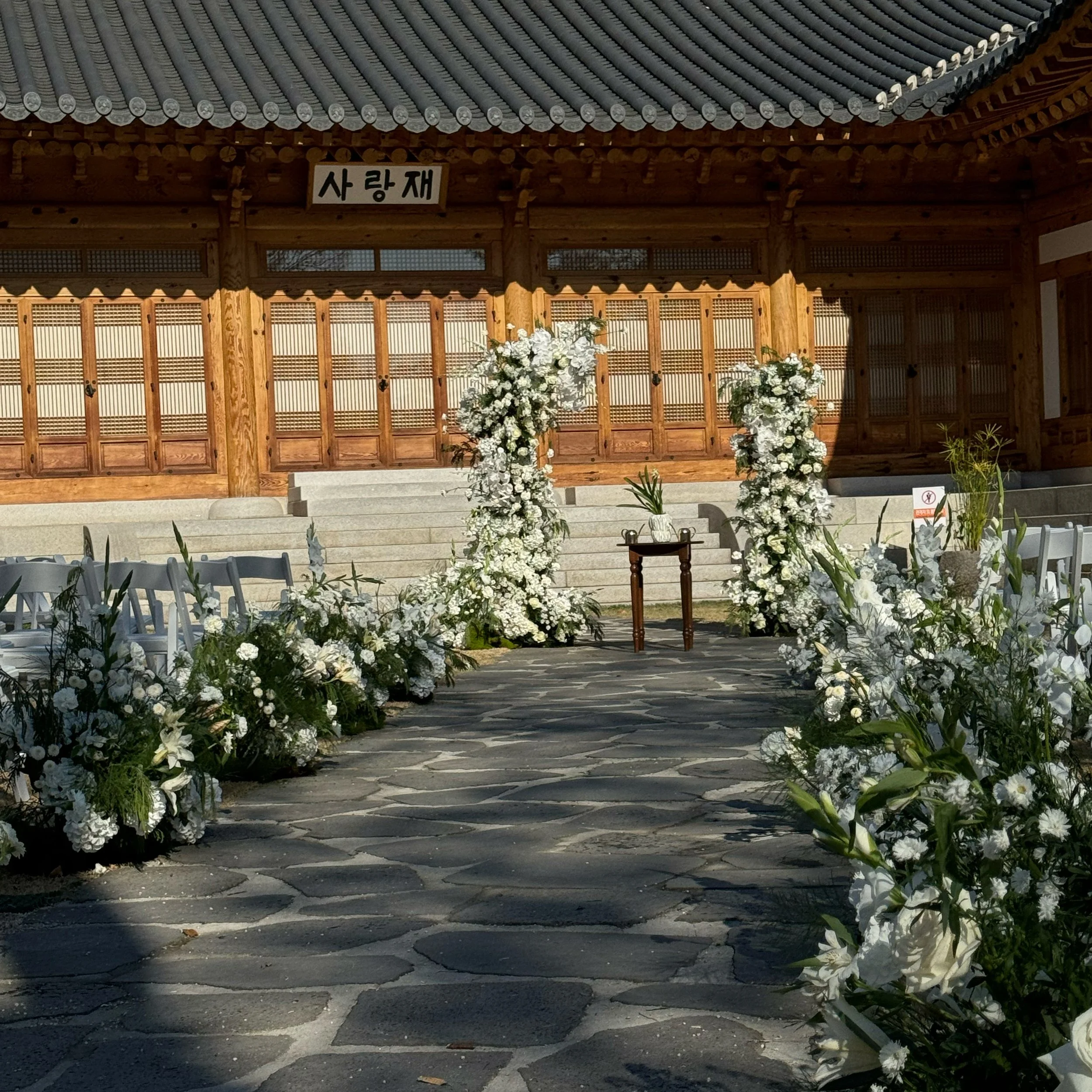 A wedding altar decorated with white flowers at a traditional Korean building with wooden architecture.