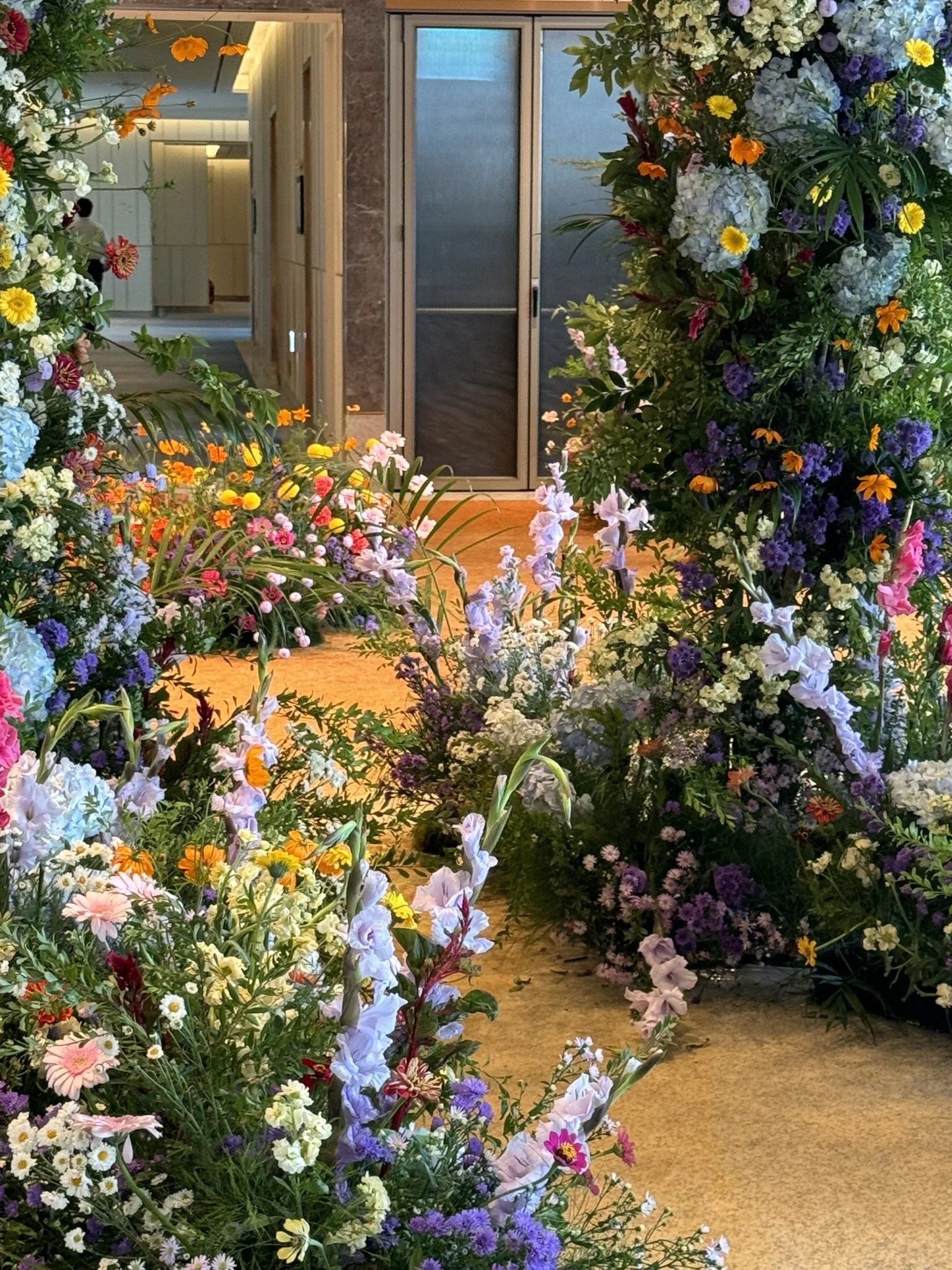 Colorful floral arrangements framing a doorway in an indoor setting, with a person in the background.