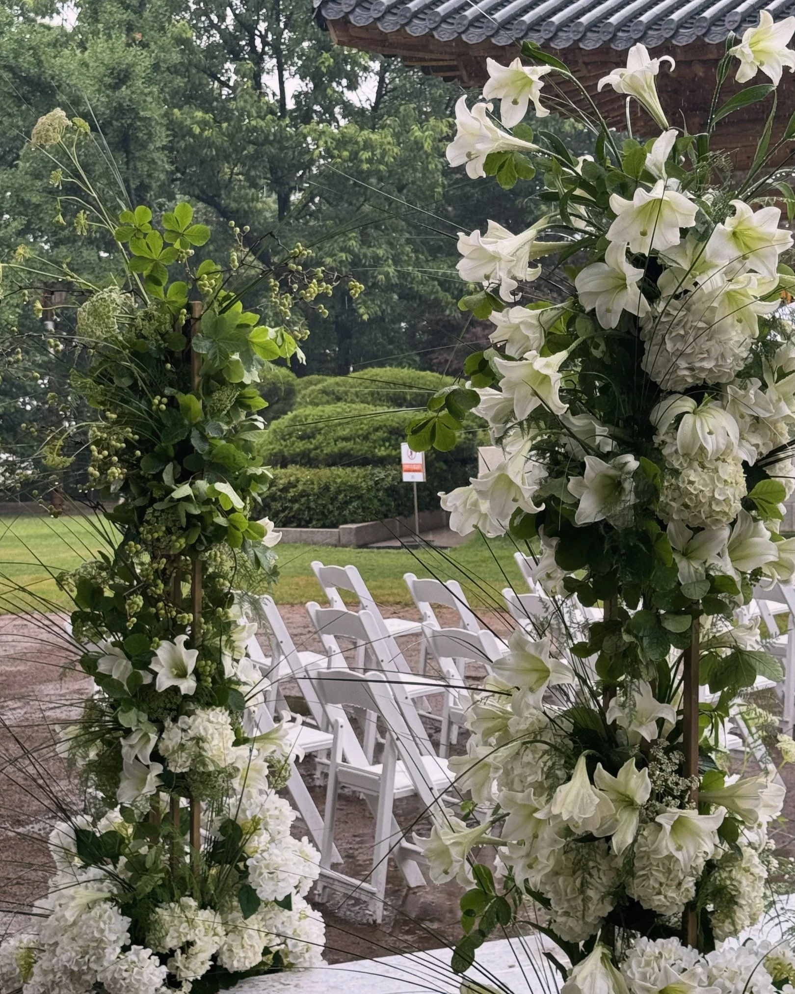 Wedding ceremony setup with white flowers and chairs outdoors.