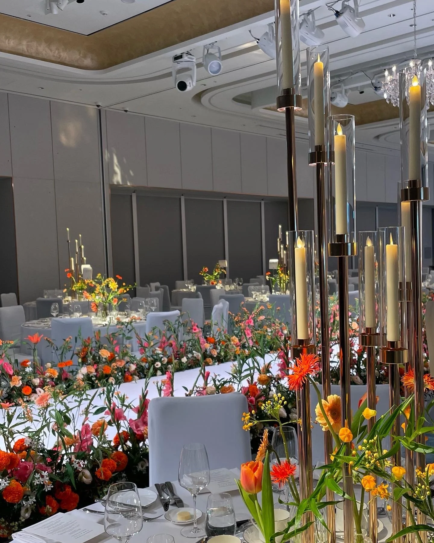Elegant banquet hall decorated with colorful flowers and tall candle holders