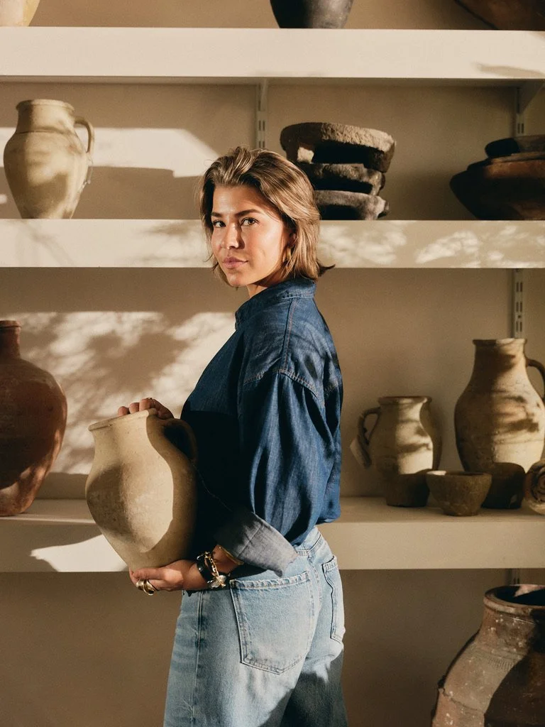 Aardewerken vaas met houten vaatwerk en potten in karaktervolle interieursetting.