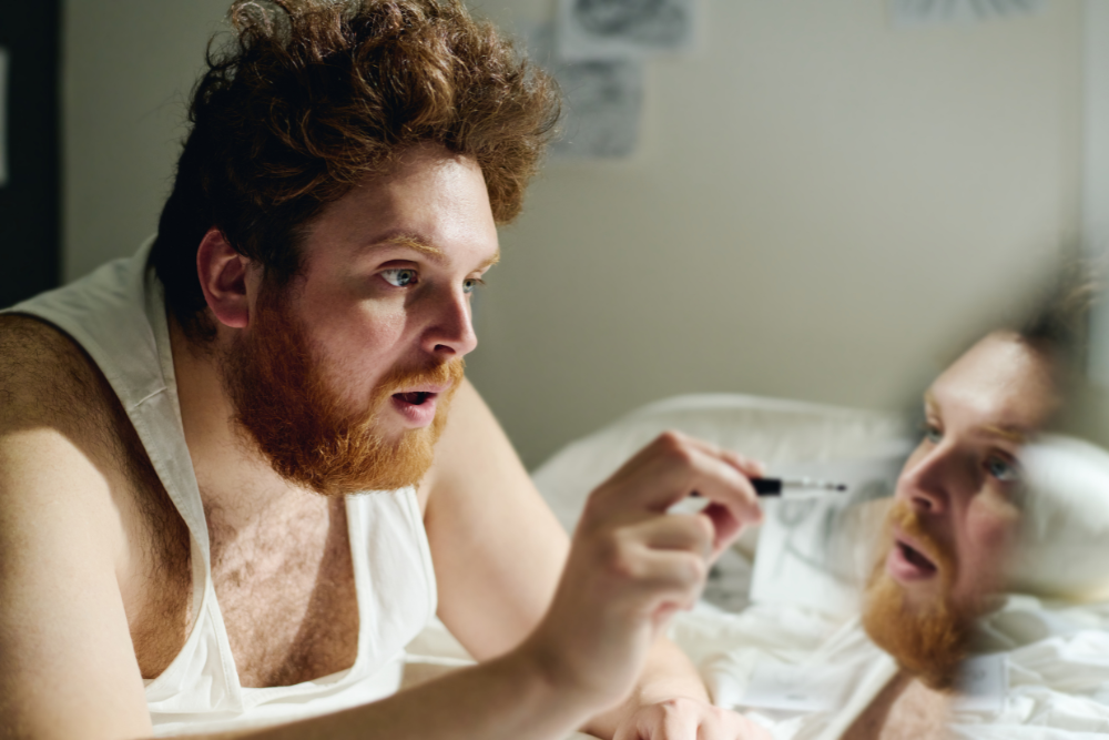 Man looking into a mirror while holding a small object near the reflection, suggesting confusion and manipulation associated with narcissistic abuse.