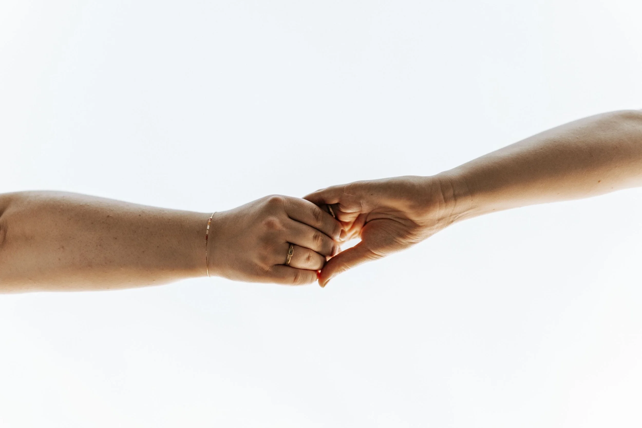 Two hands reaching toward one another, symbolizing trauma recovery, emotional healing, and support during the healing journey.