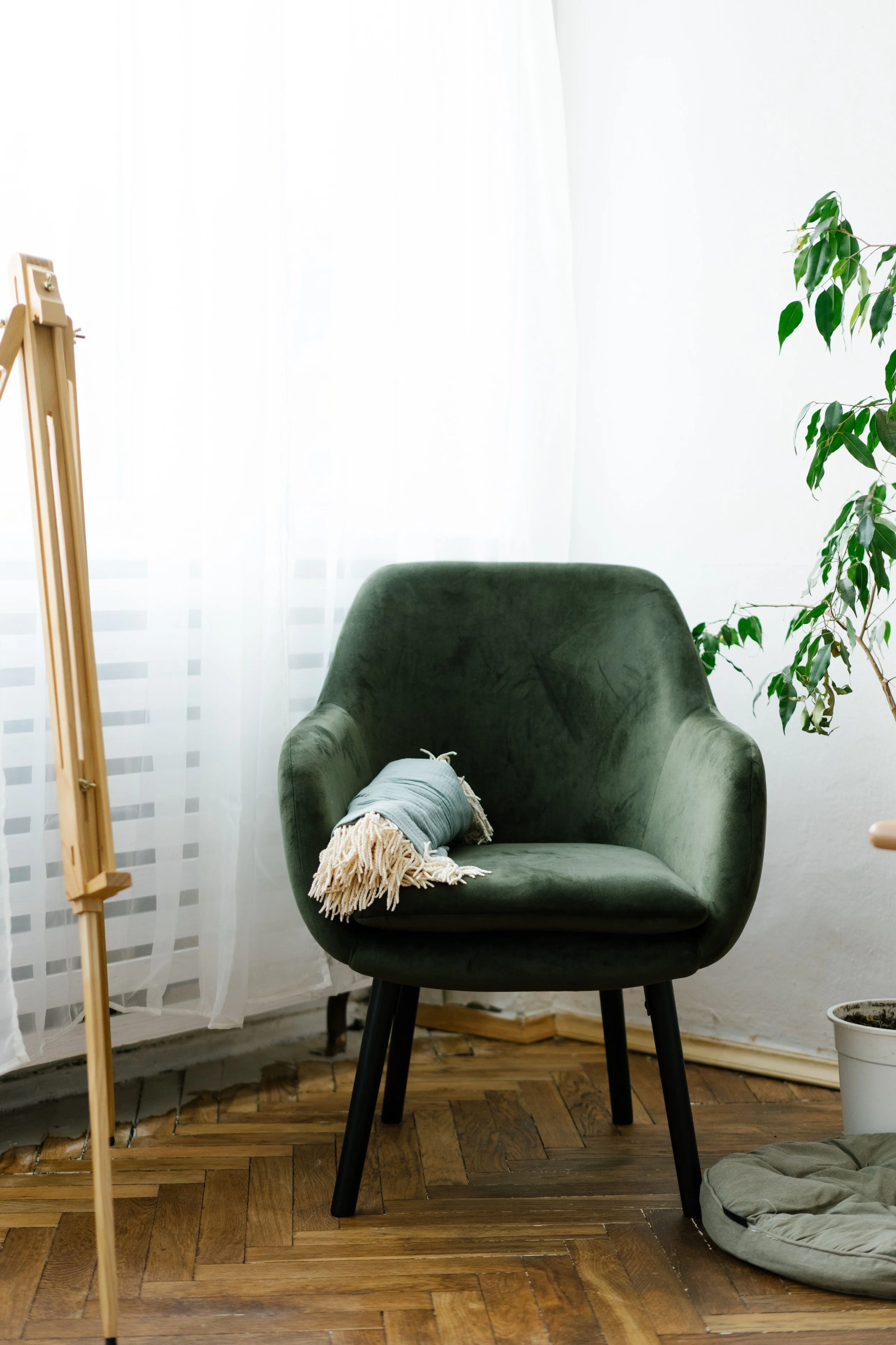 Sunlit reading chair beside a window, symbolizing emotional safety, learning to rest after trauma, and nervous system healing.