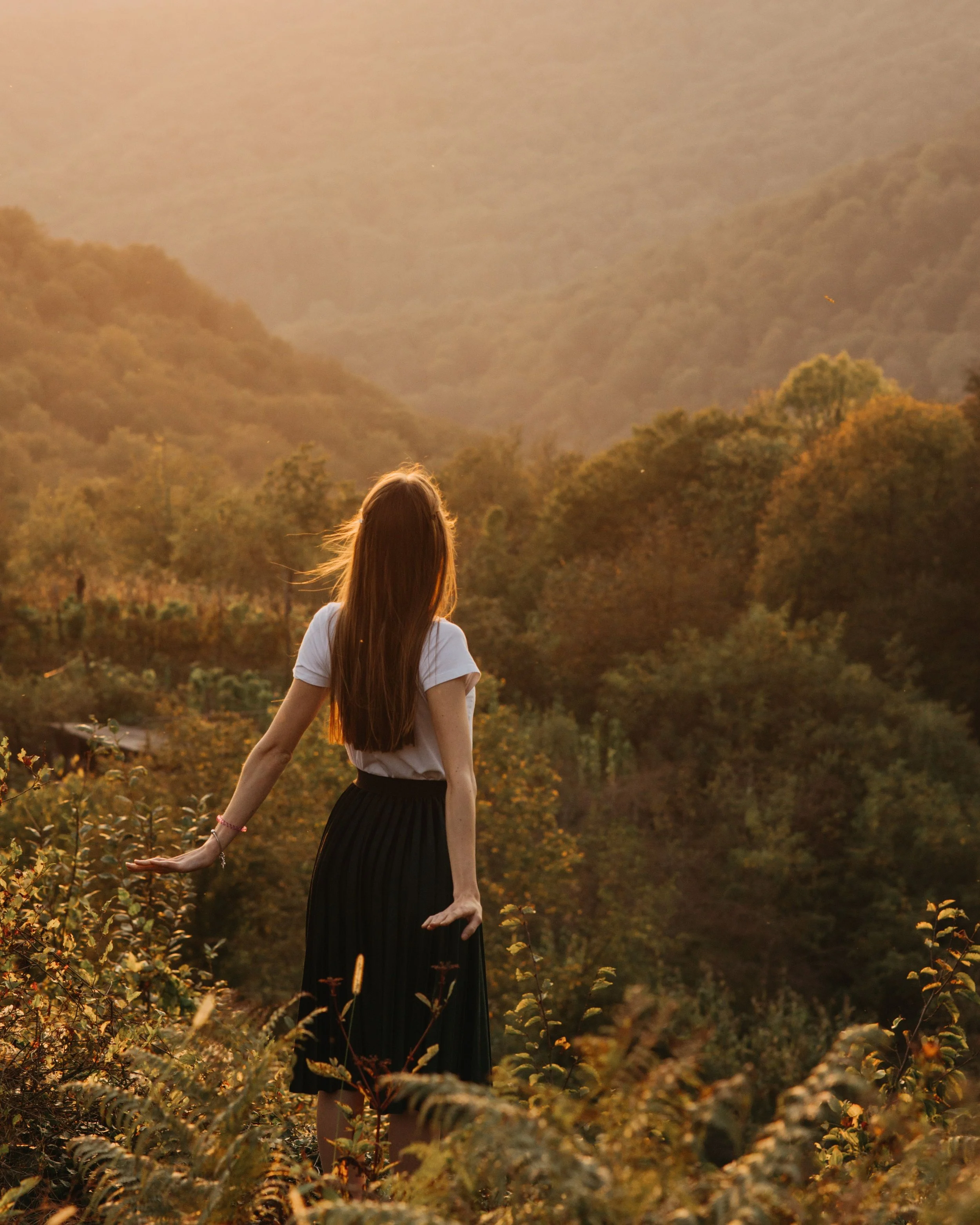 Woman standing in a sunlit valley, symbolizing healing after relational trauma, emotional safety, and nervous system recovery.