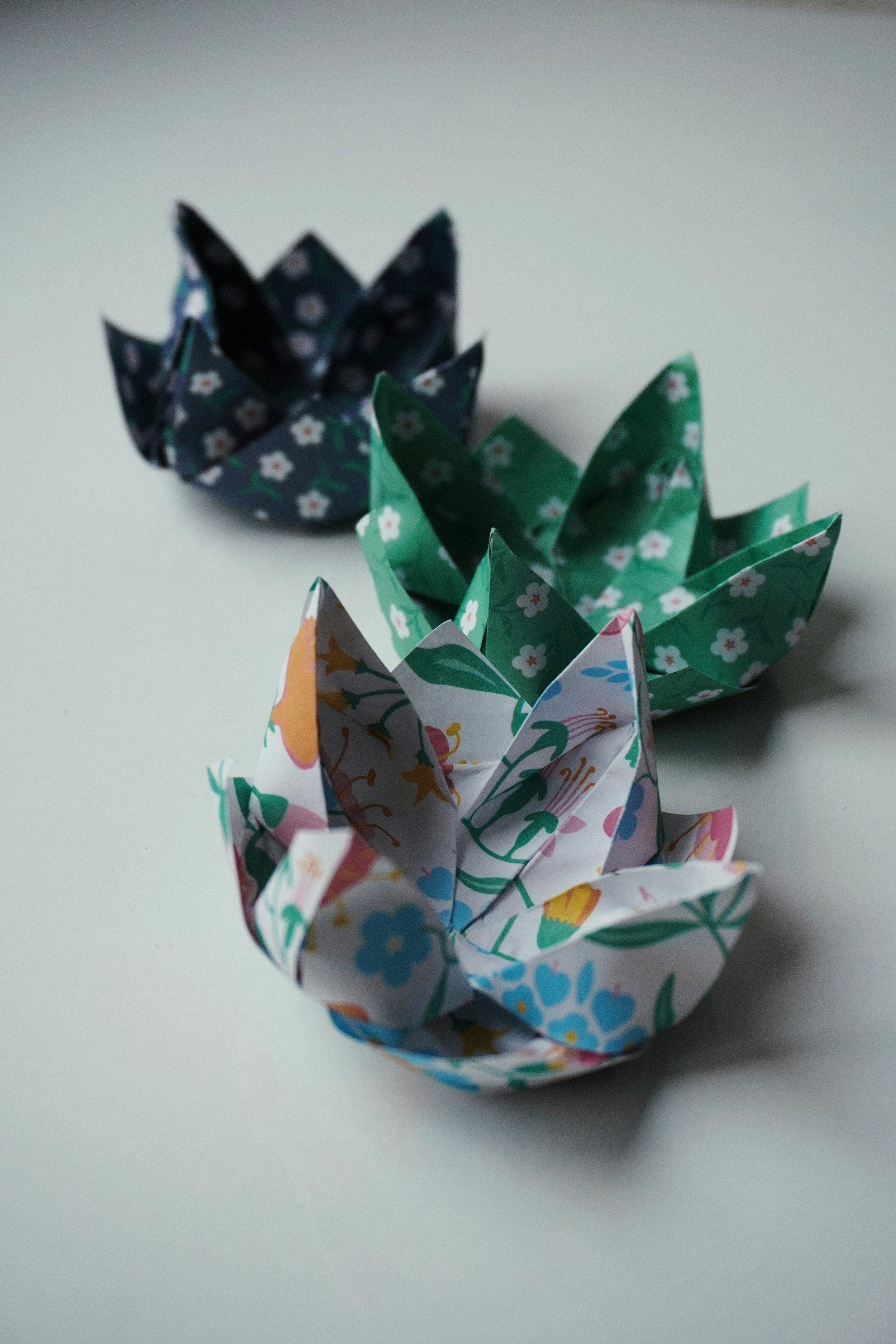 Three colorful origami paper flowers arranged on a white surface. YUMIDON is a cultural hub in Hammersmith and Fulham, London