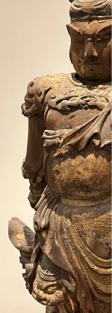 Een close-up van een oude, keramische of bronzen beeldhouwwerk van Kuan Ti met gedetailleerde kleding en ornamenten.