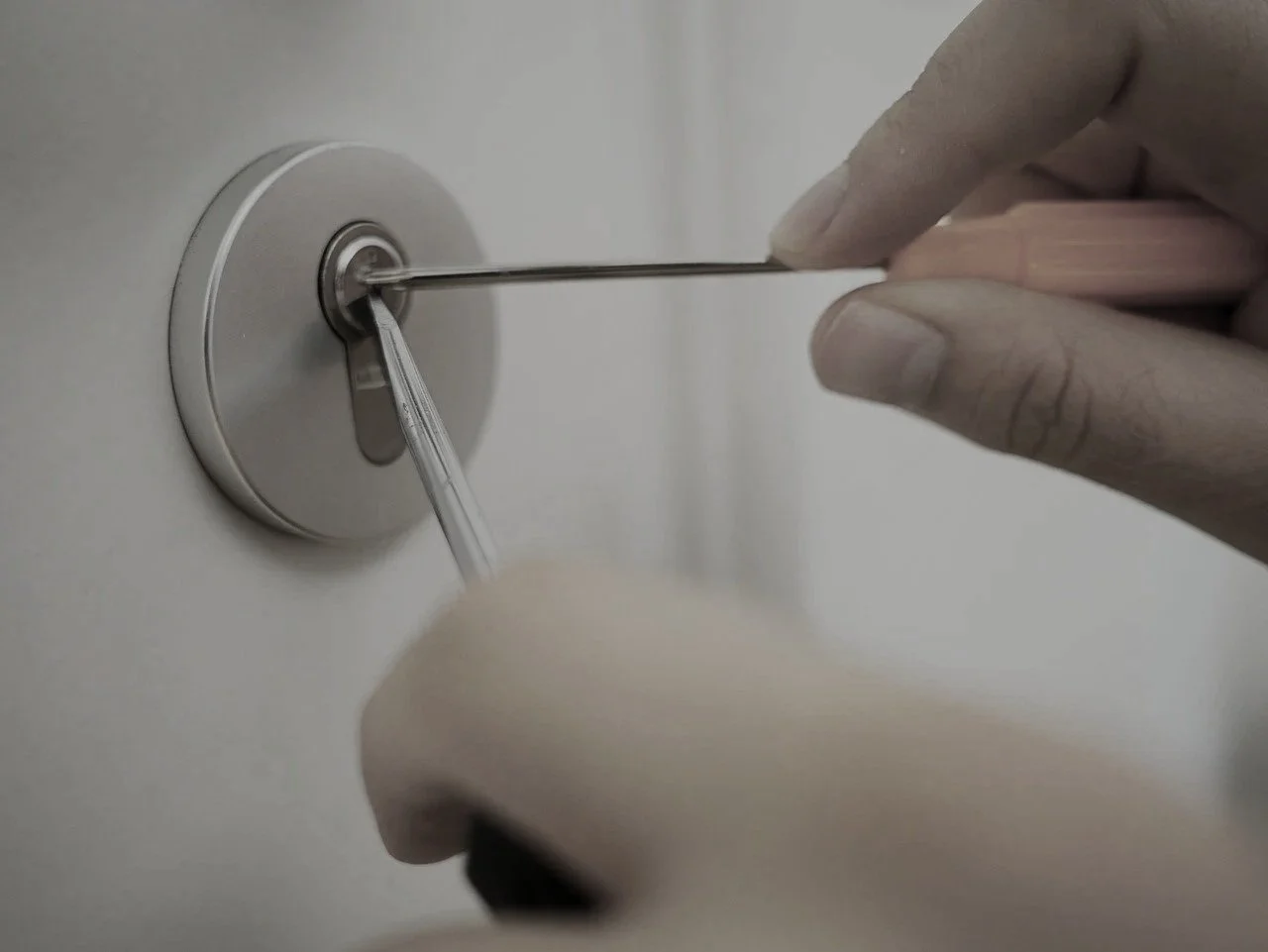 Nahaufnahme einer Hand, die mit einem picking Tool versucht ein Türschloss zu öffnen.