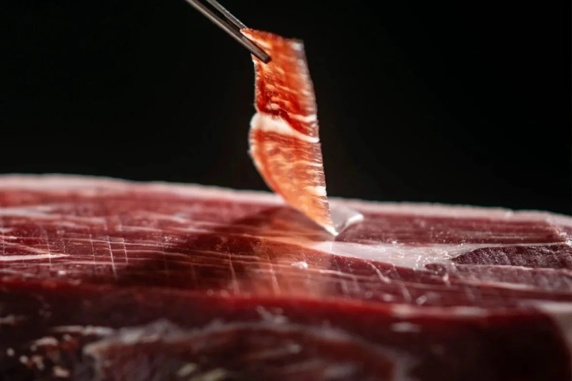 Cured leg of ham hanging on hooks.