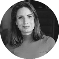 Schwarz-Weiß-Porträt einer Frau mit mittellangen Haaren, lächelnd, vor dunklem Hintergrund.