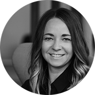 Schwarz-weiß-Porträt einer jungen Frau mit langen Haaren, lächelnd, vor einem dunklen Hintergrund