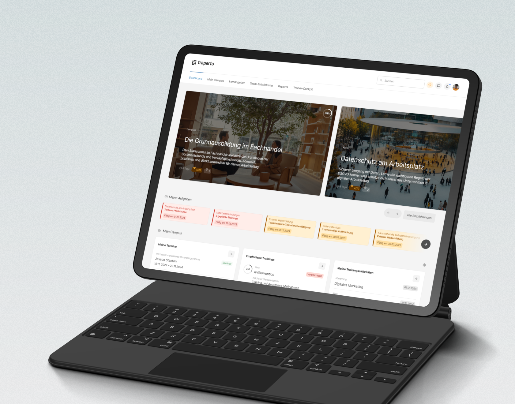 Ein tabletähnliches Gerät mit einer Tastatur zeigt eine Schulungsplattform mit Kursen und Trainingssitzungen auf dem Bildschirm. Das Layout ist hell mit mehreren Karten für verschiedene Kursthemen.
