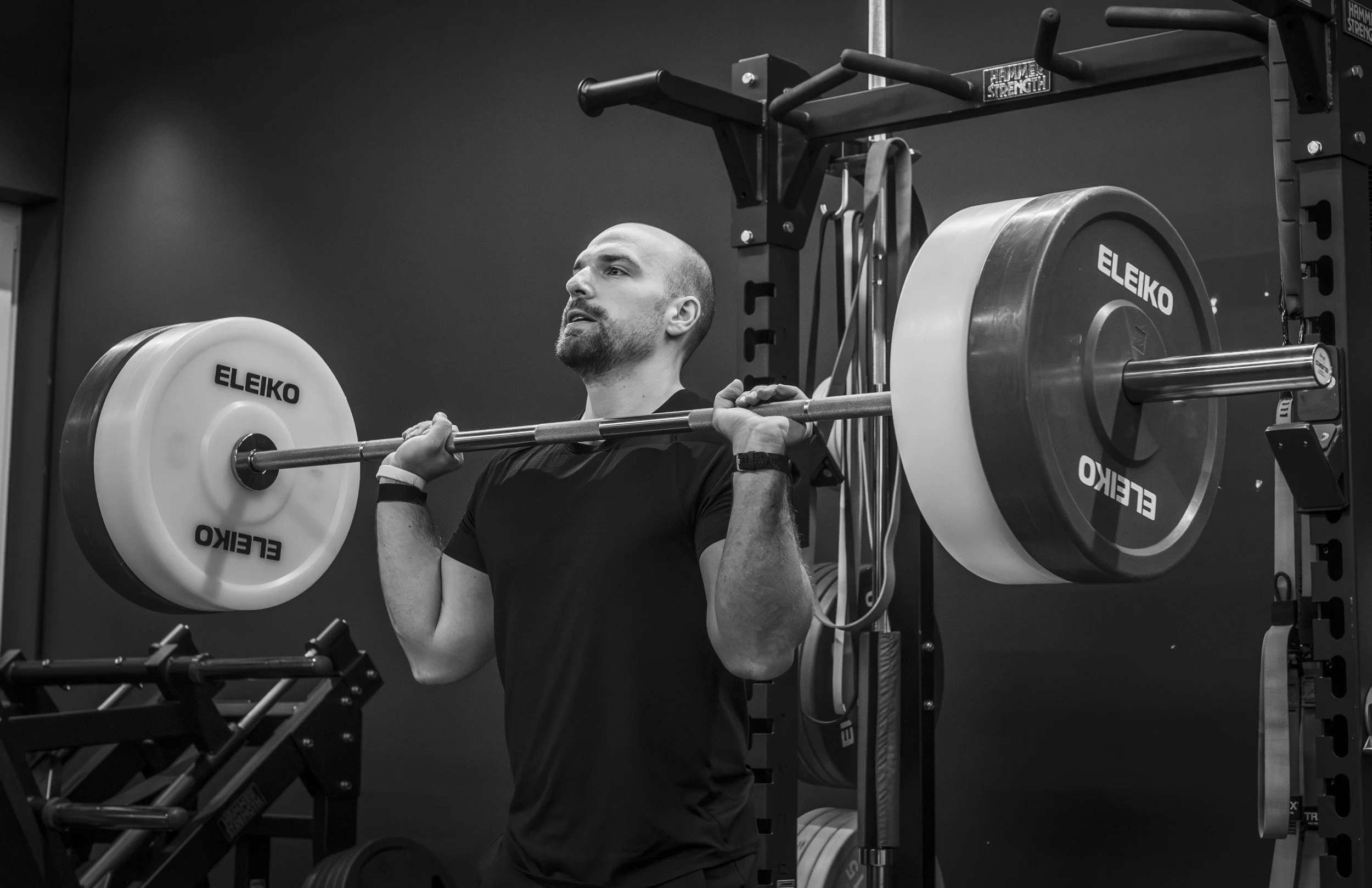 Mann hebt eine schwere Langhantel beim Krafttraining in einem Fitnessstudio.