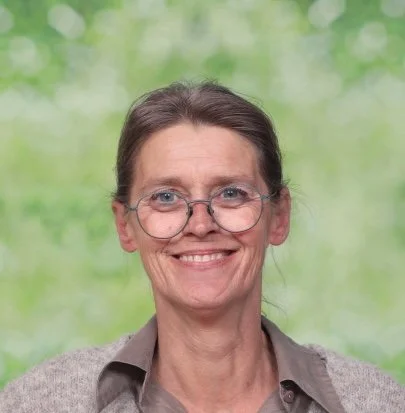 Een lachende man met kort, bruin haar, op een witte achtergrond.