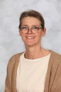 Een lachende man met kort, bruin haar, op een witte achtergrond.