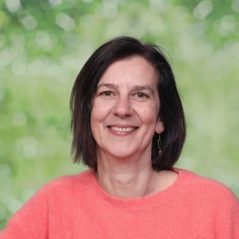 Portret van een vrouw met korte, darke haar en een witte blouse, glimlachend