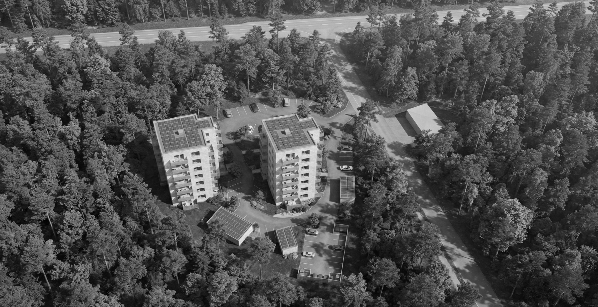 Aerial view of two modern apartment buildings with solar panels on the roofs, surrounded by trees, parking lots, and roads.