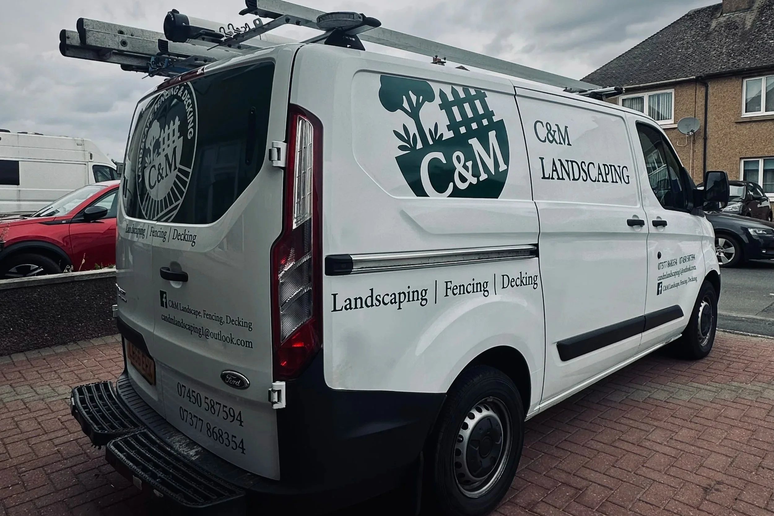White service van with C&M Landscaping logo, and text for landscaping, fencing, and decking. Contact info and social media handle visible on the back and side.