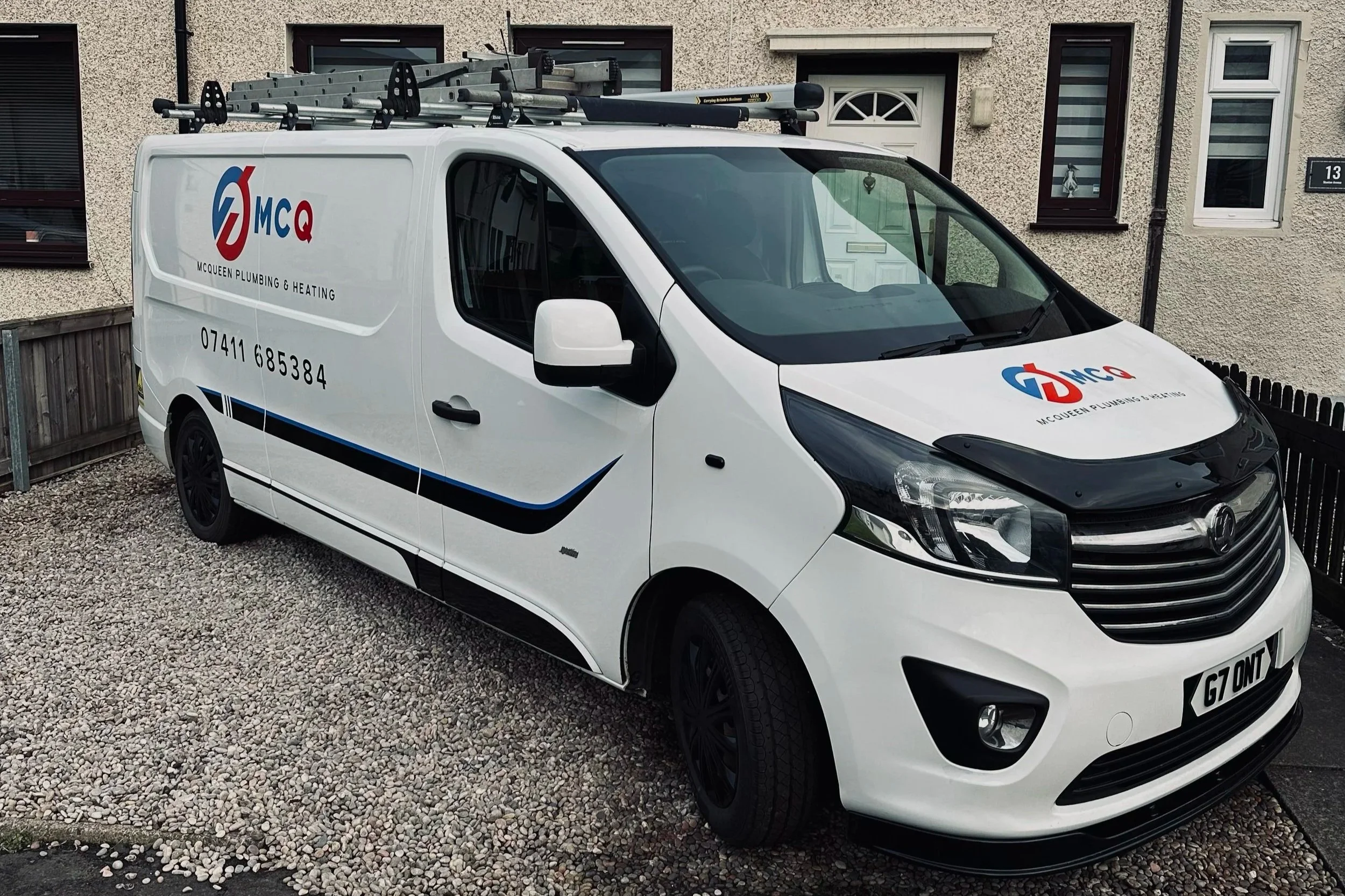 White company van with black accents and roof rack, parked on gravel, with company logo and phone number.