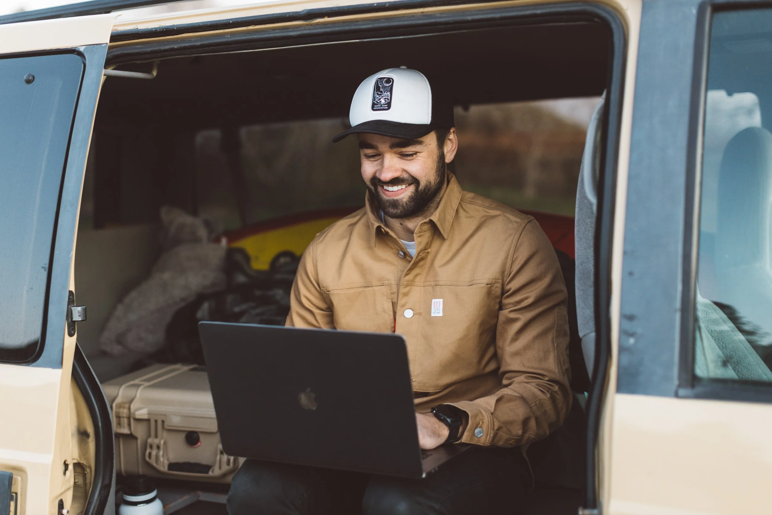Content creator sitting in his van working on his macbook pro laptop during a branding photoshoot in the Boise foothills.