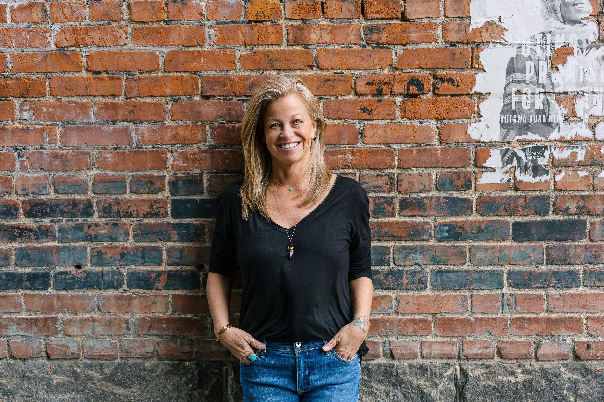 Female business owner leaning against brick wall and smiling during a branding photoshoot in downtown Boise