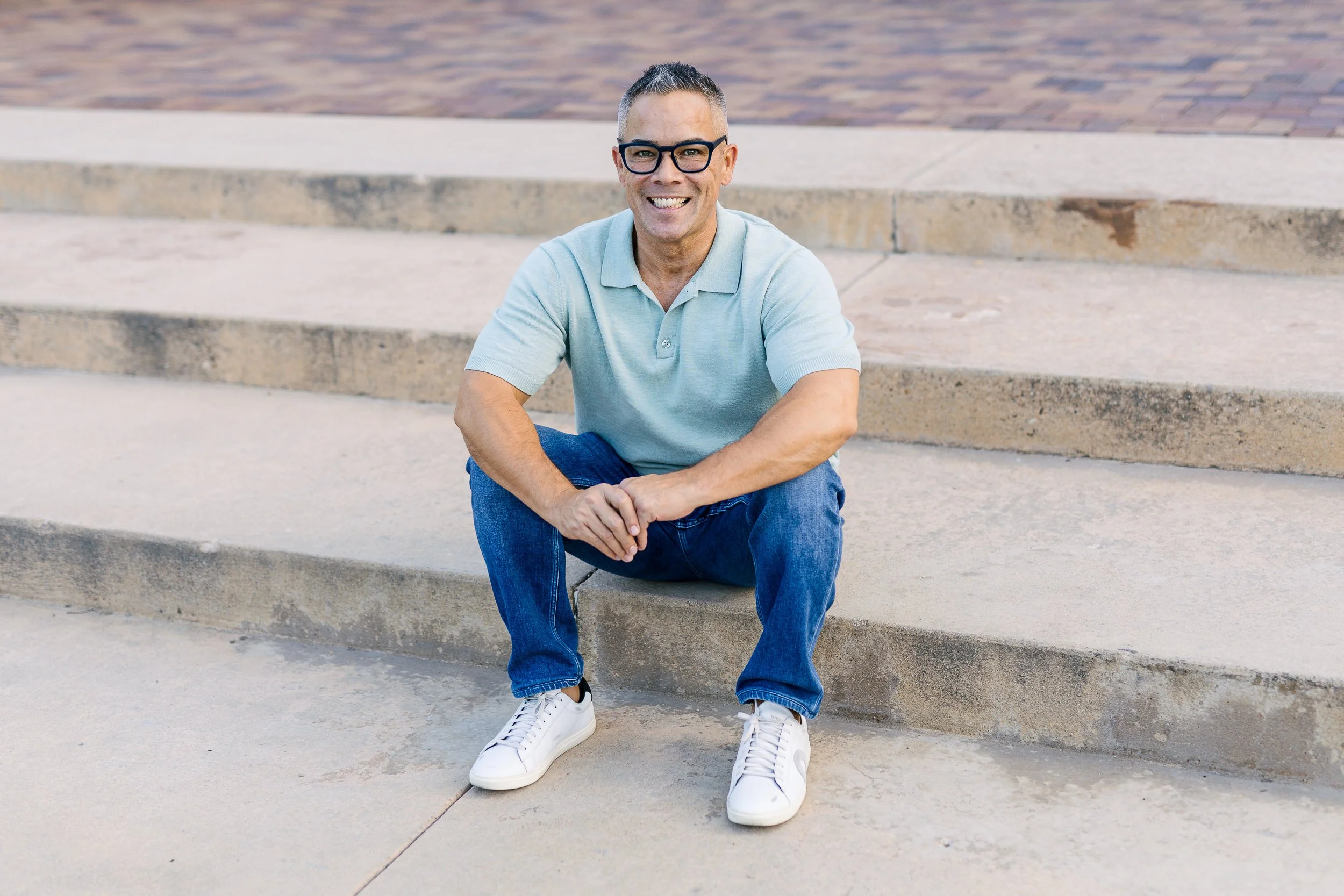 Mortgage broker smiling sitting on the stairs at the Boise Train Depot during a branding photography session.