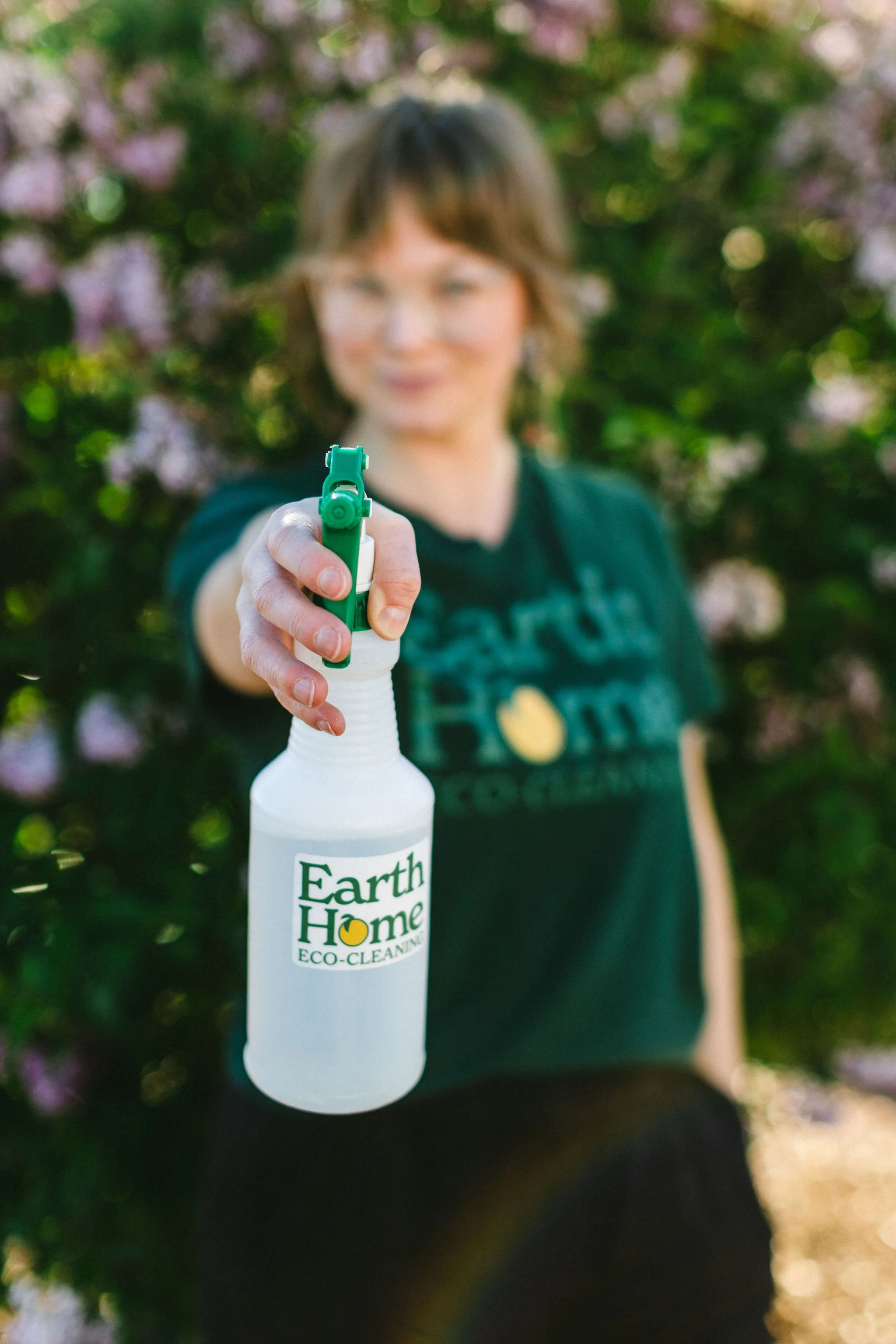 Creative branding photo of a woman business owner holding a spray bottle and pointing it towards the camera during a branding photography session in Boise, Idaho.