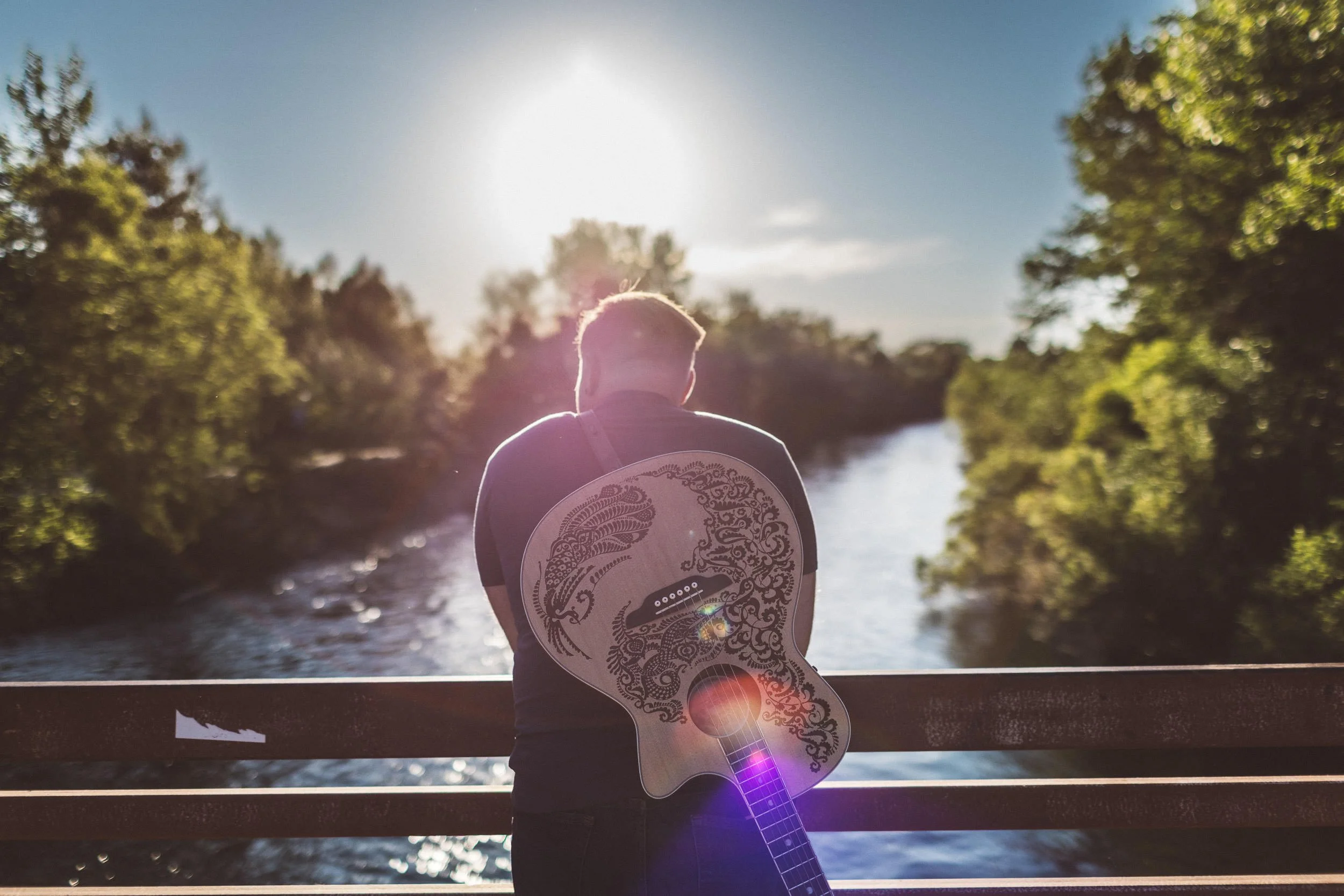 Man leaning against Friendship Bridge on the Boise River Greenbelt, during a branding photoshoot.