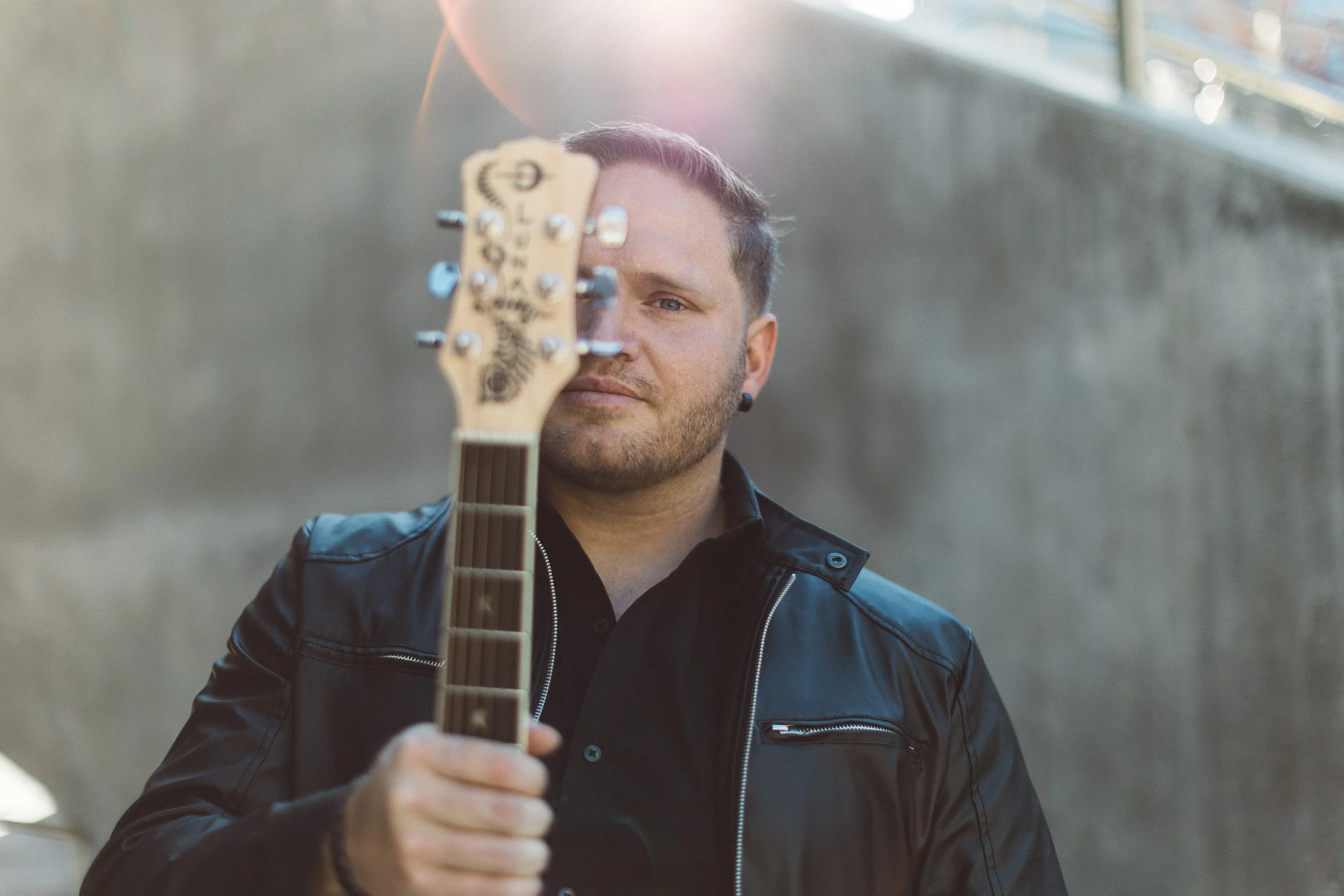 Man holding up guitar during a personal branding photoshoot at Jump in Downtown Boise.