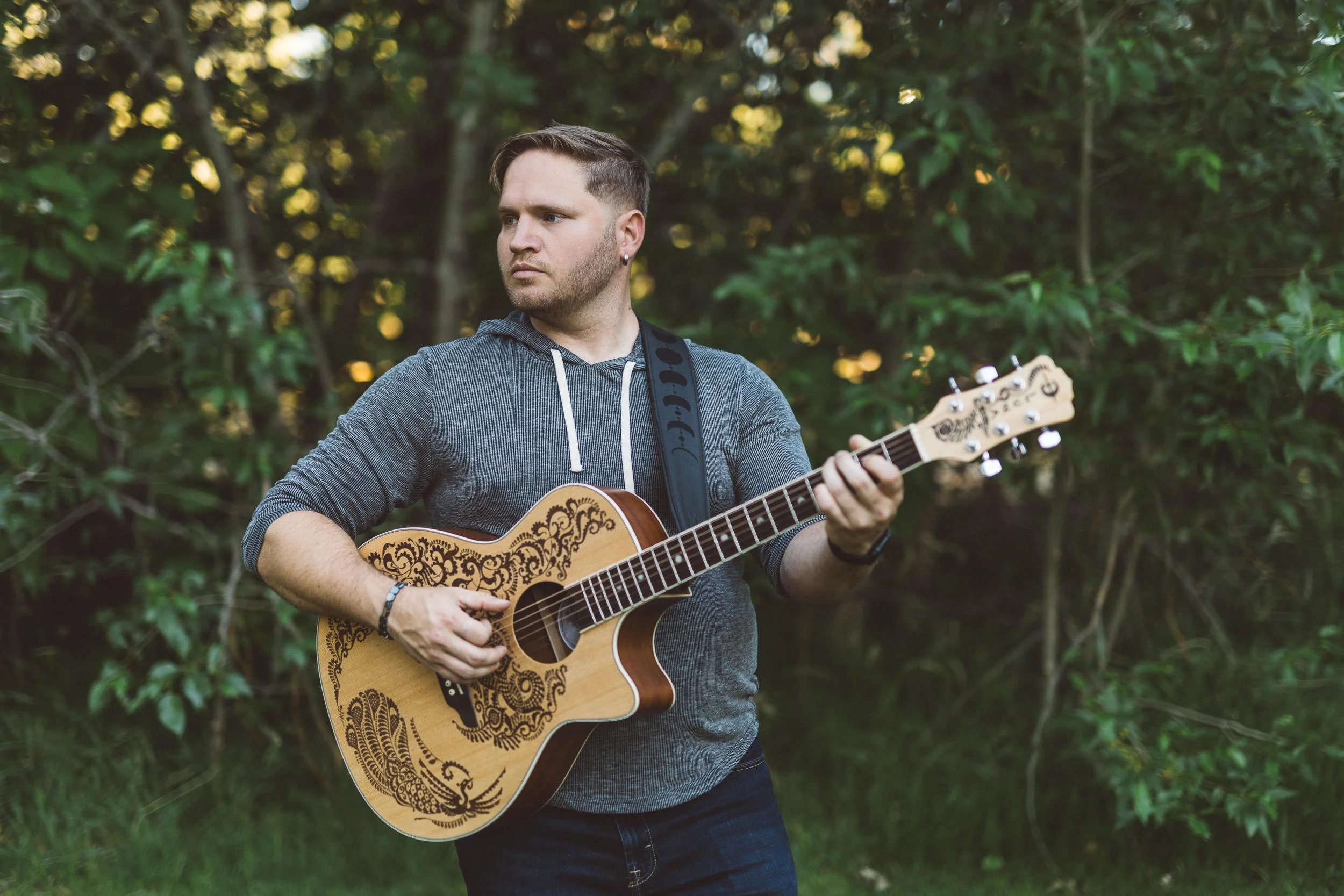 Musician playing guitar and looking away from the camera during a branding photoshoot at Julia Davis Park.