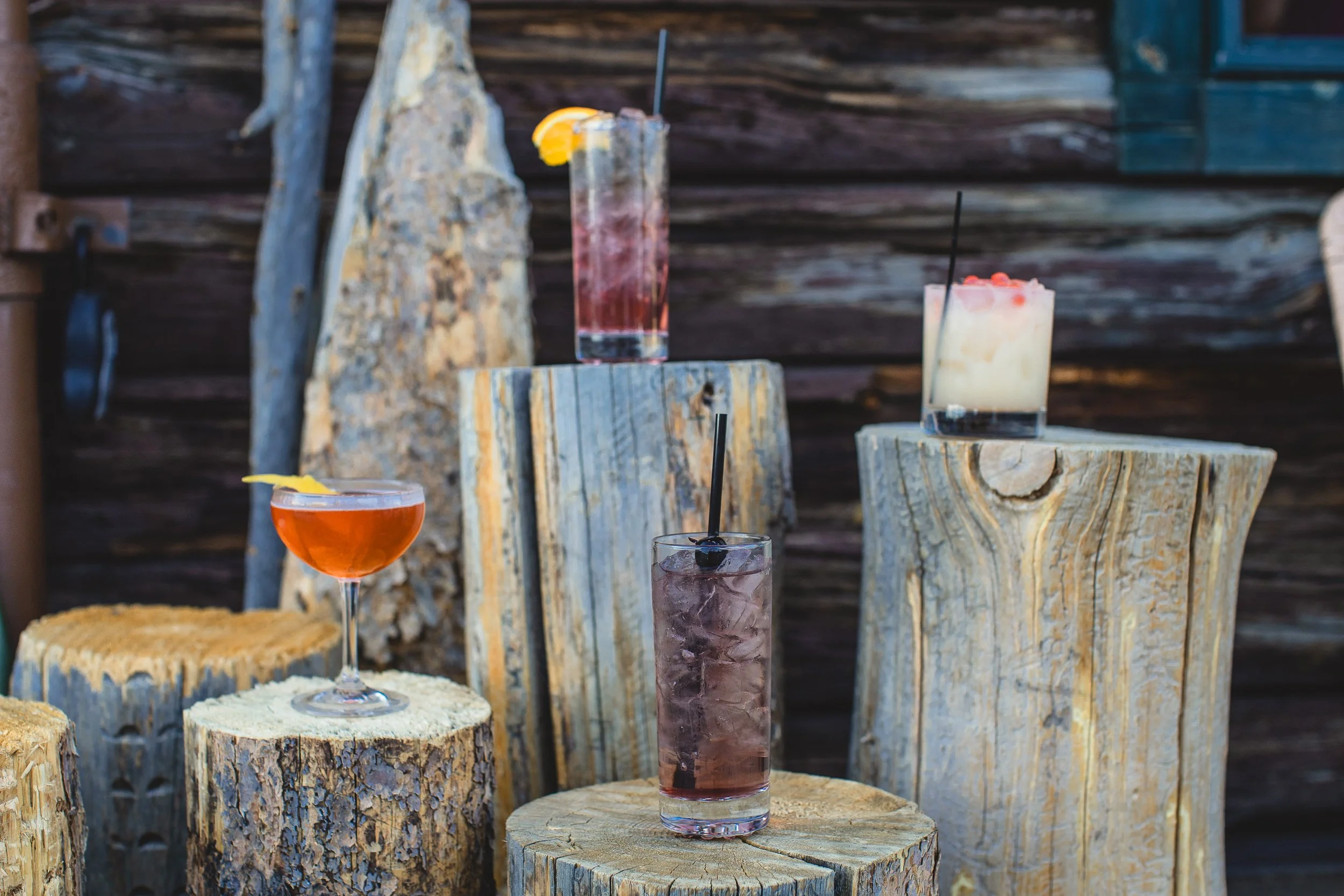 Cocktails sitting on logs outside of the bar Rod and Gun during a branding photo session in Stanley Idaho.