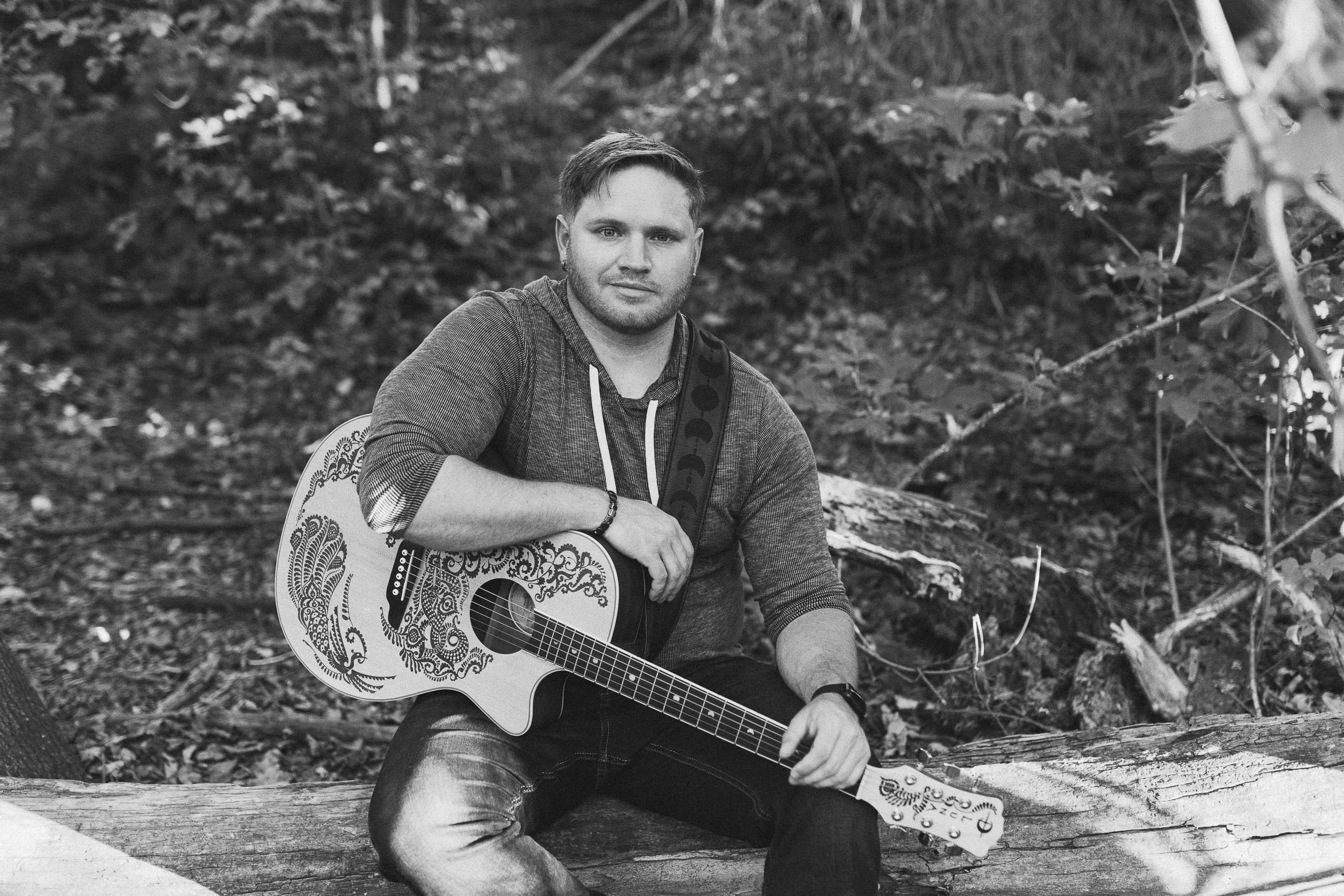 Musician smirking at camera during a branding photography session on the Boise River Greenbelt.
