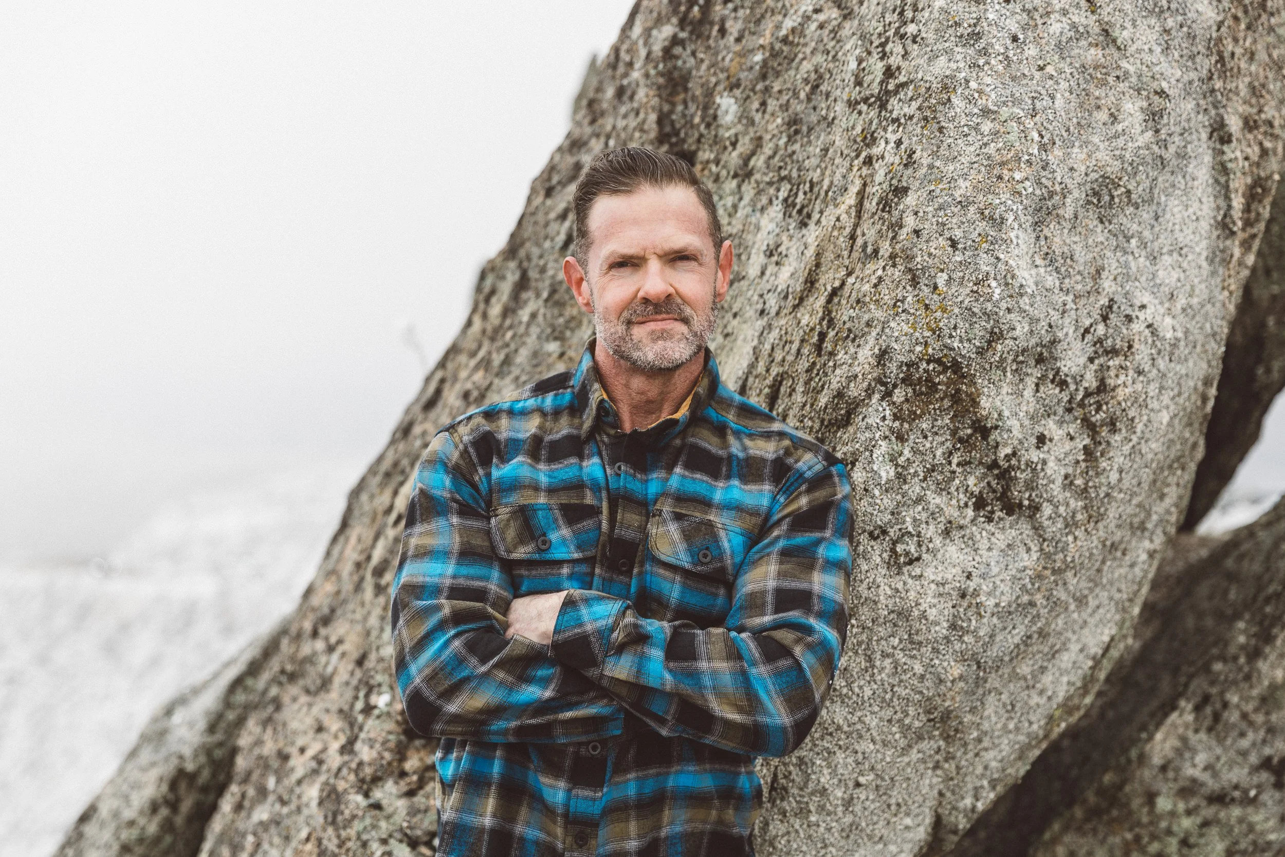 Boise branding photographer capturing outdoor authentic branding photos for an entrepreneur in the Boise foothills at a rock outcropping on Bogus Basin Road on a foggy day in January.