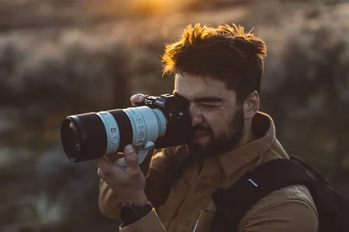 Creative portrait of a professional photographer taking a picture at sunset in the foothills, during a personal branding photoshoot in Boise, Idaho.