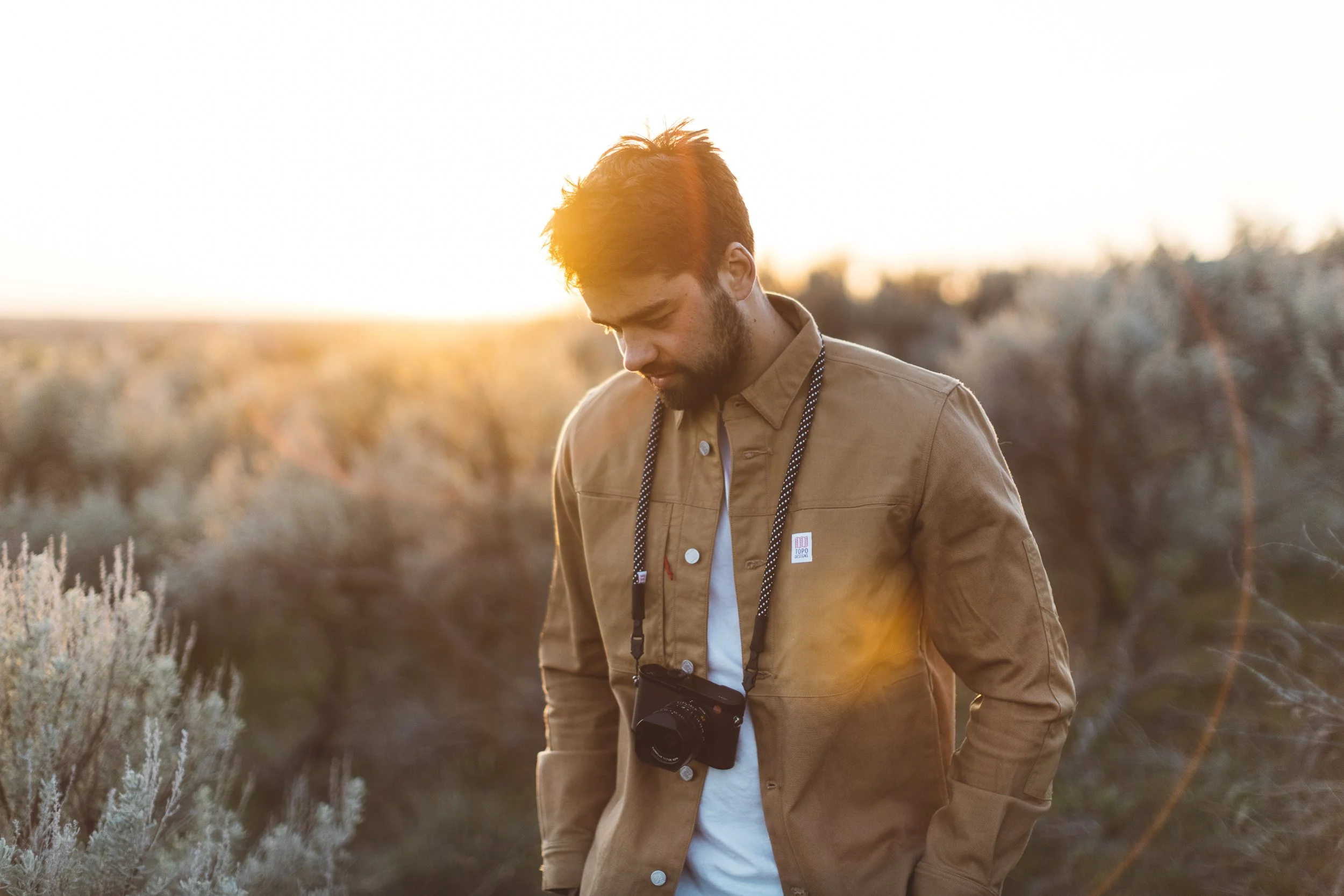 Photographer in the Boise foothills looks towards the ground during a branding photography session at sunset.