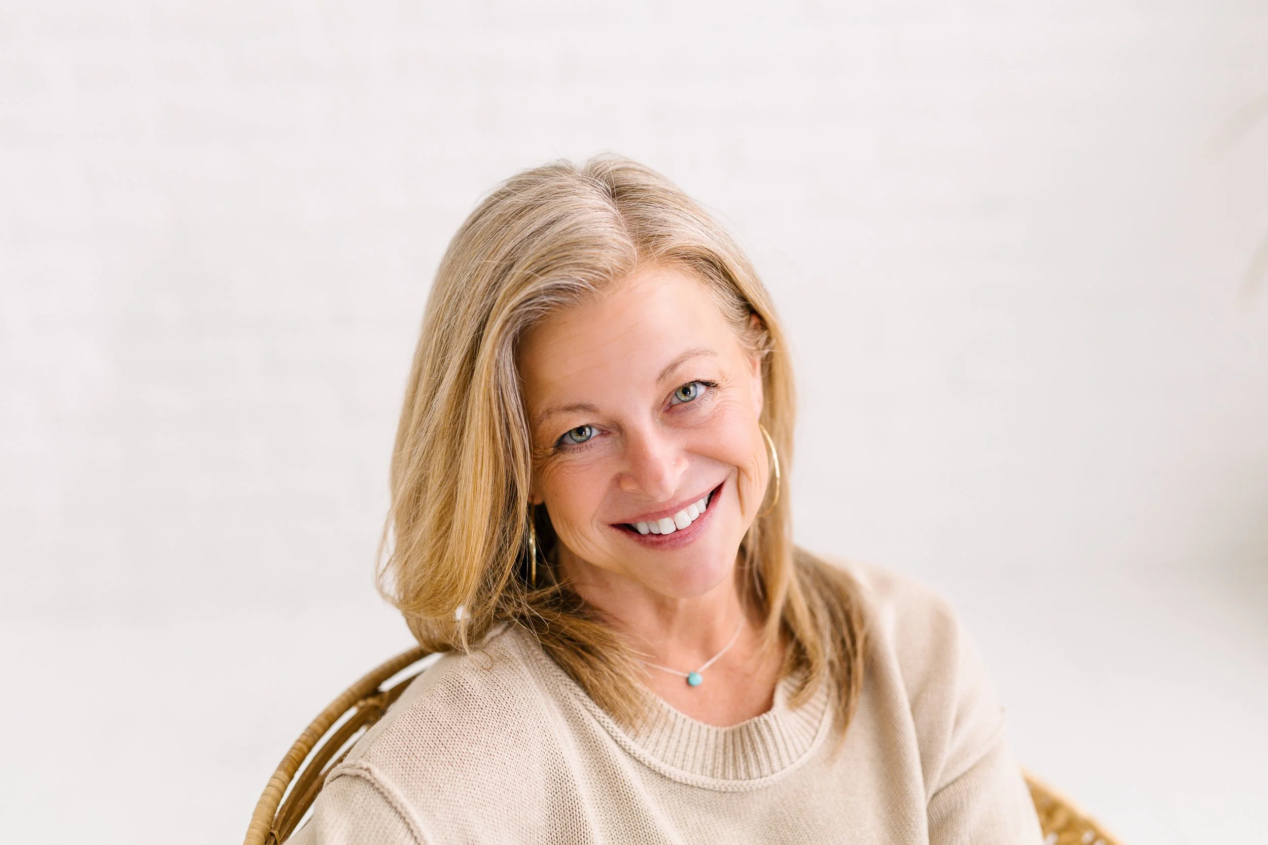Female business owner smiling in front of a white brick wall during a branding photography session in a studio in downtown Boise.