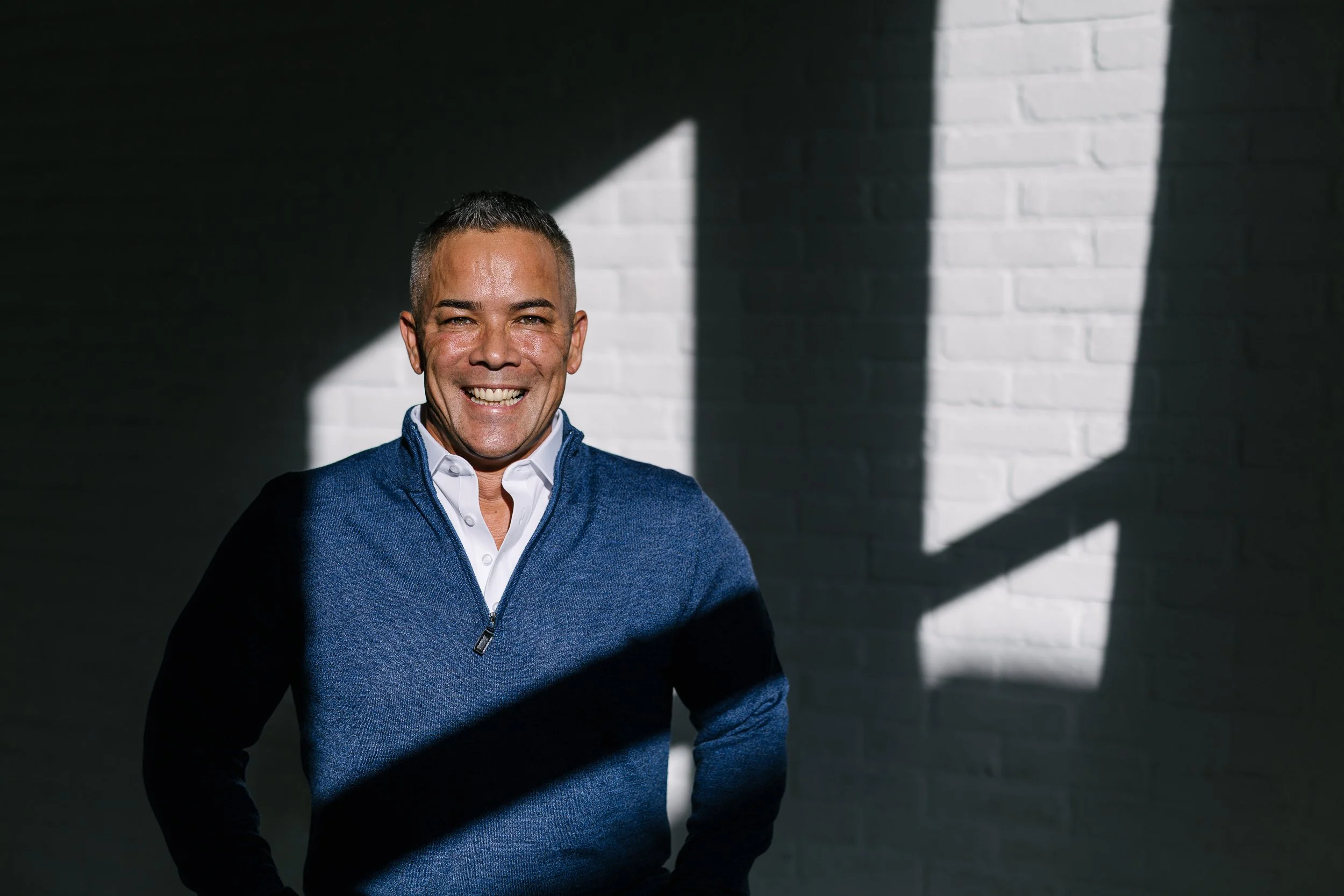 Business owner standing in natural window light smiling during a branding photography session in a studio in downtown boise.