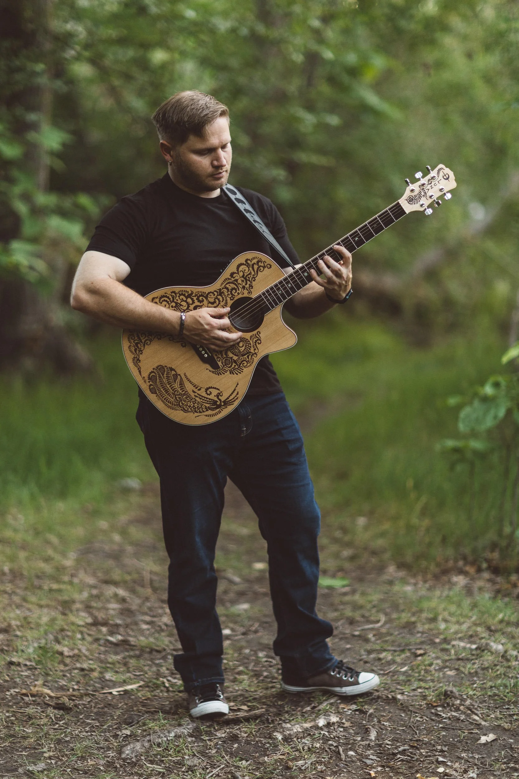 Man playing guitar during a branding photoshoot on the Boise River Greenbelt.