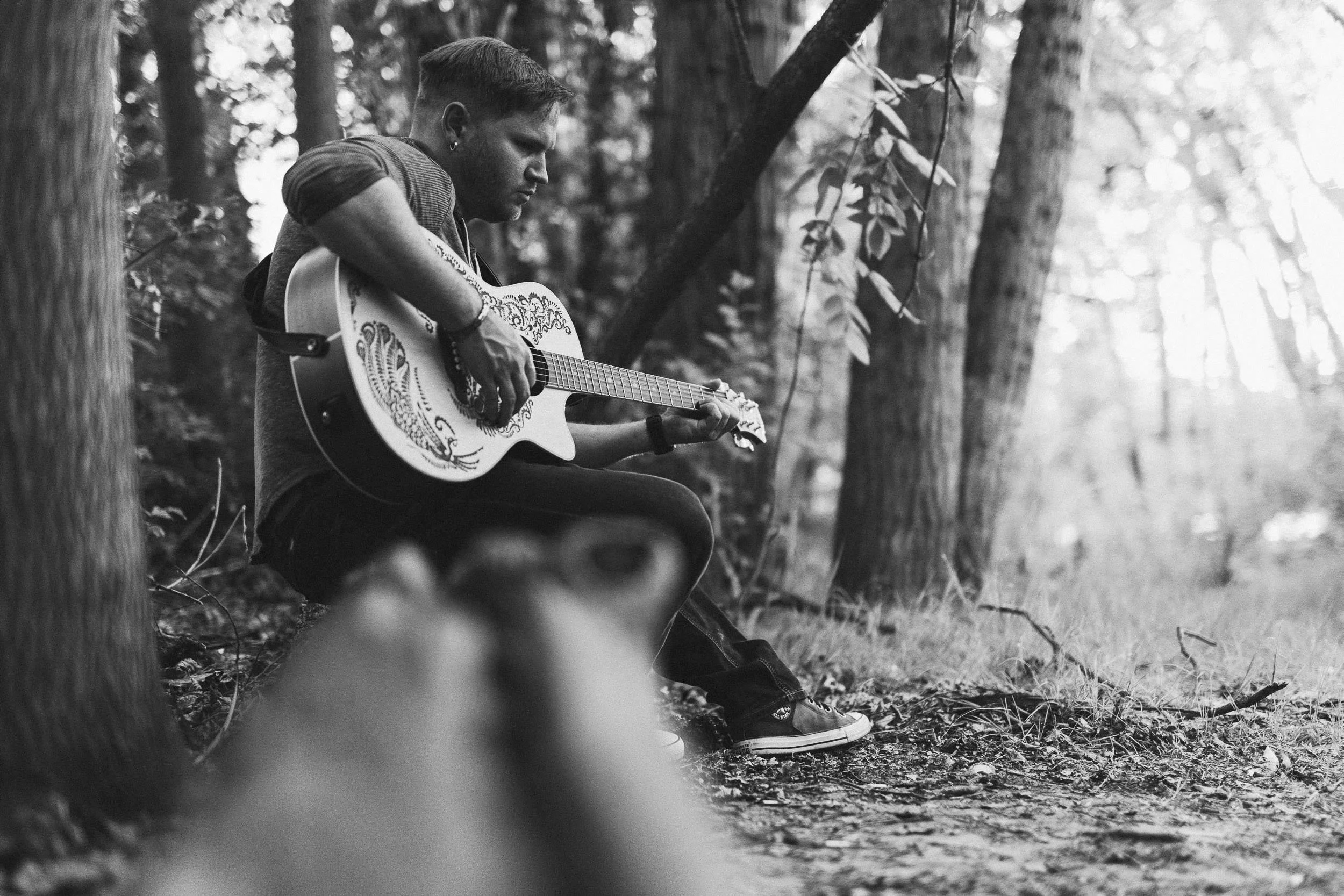 Local musician playing guitar during a branding photoshoot on the Boise River Greenbelt.