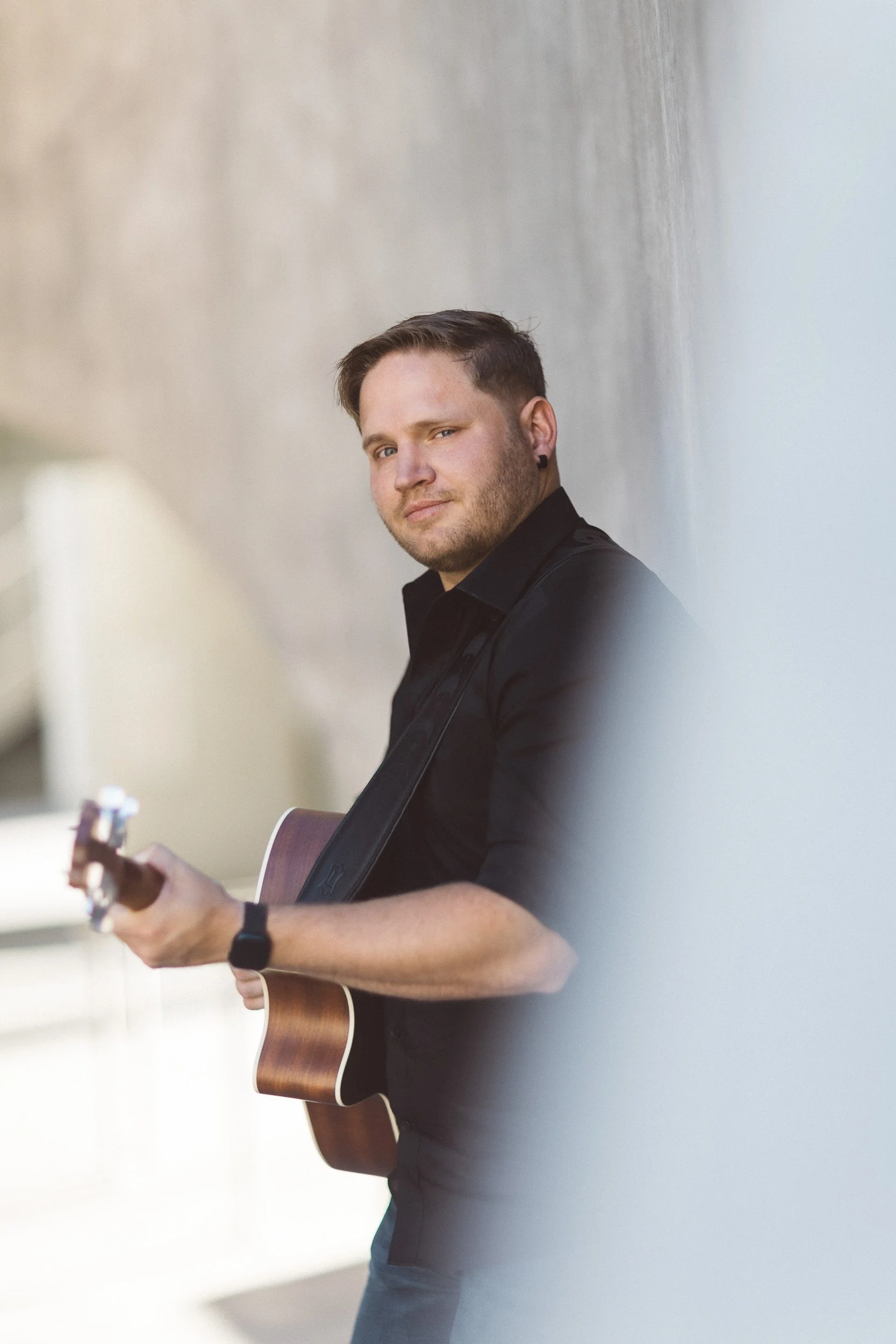 Man holding a guitar looking at the camera during a personal branding photoshoot at Jacks Urban Meeting Place in downtown Boise.