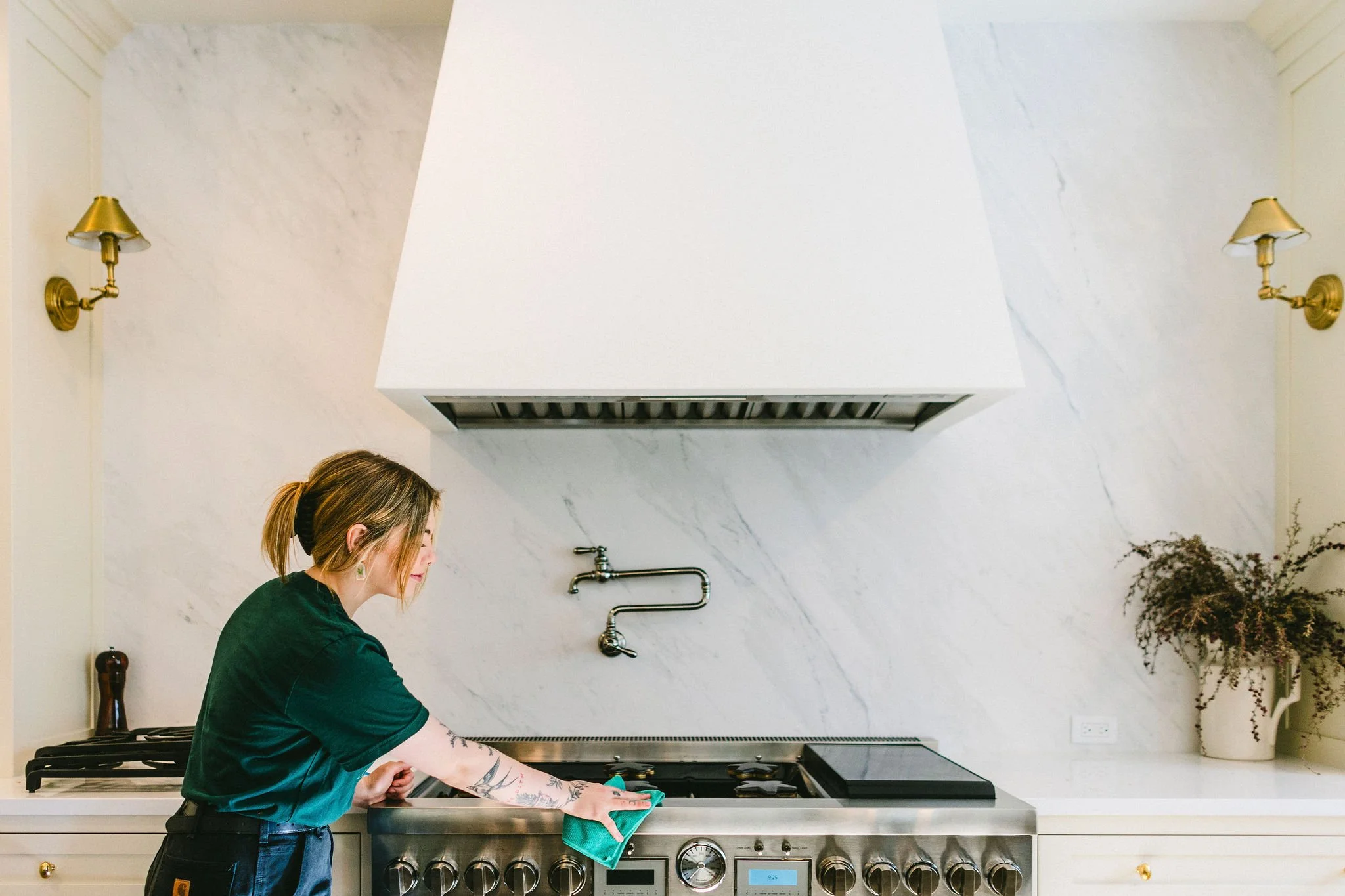 Branding photo of a woman house cleaner cleaning a stove in a private home during a branding photoshoot session in the North End in Boise, Idaho.