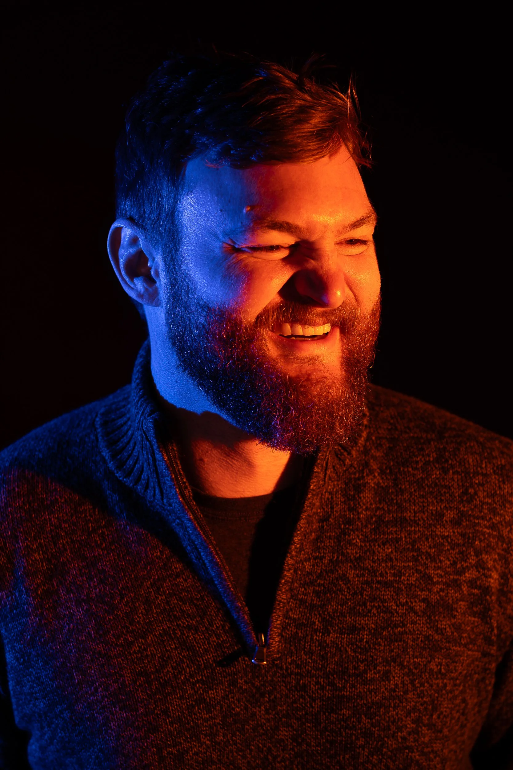 Marketing agency digital director photographed with creative blue and orange lighting against a black backdrop during a branding photoshoot in Boise.