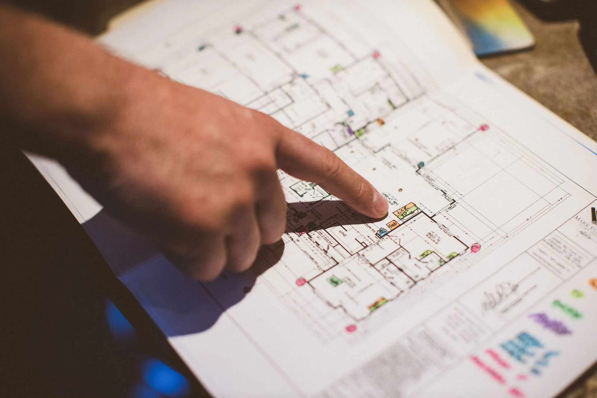 Close-up photo of a person's hand pointing at an architectural blueprint on a table during a branding photoshoot in Newberg, Oregon.