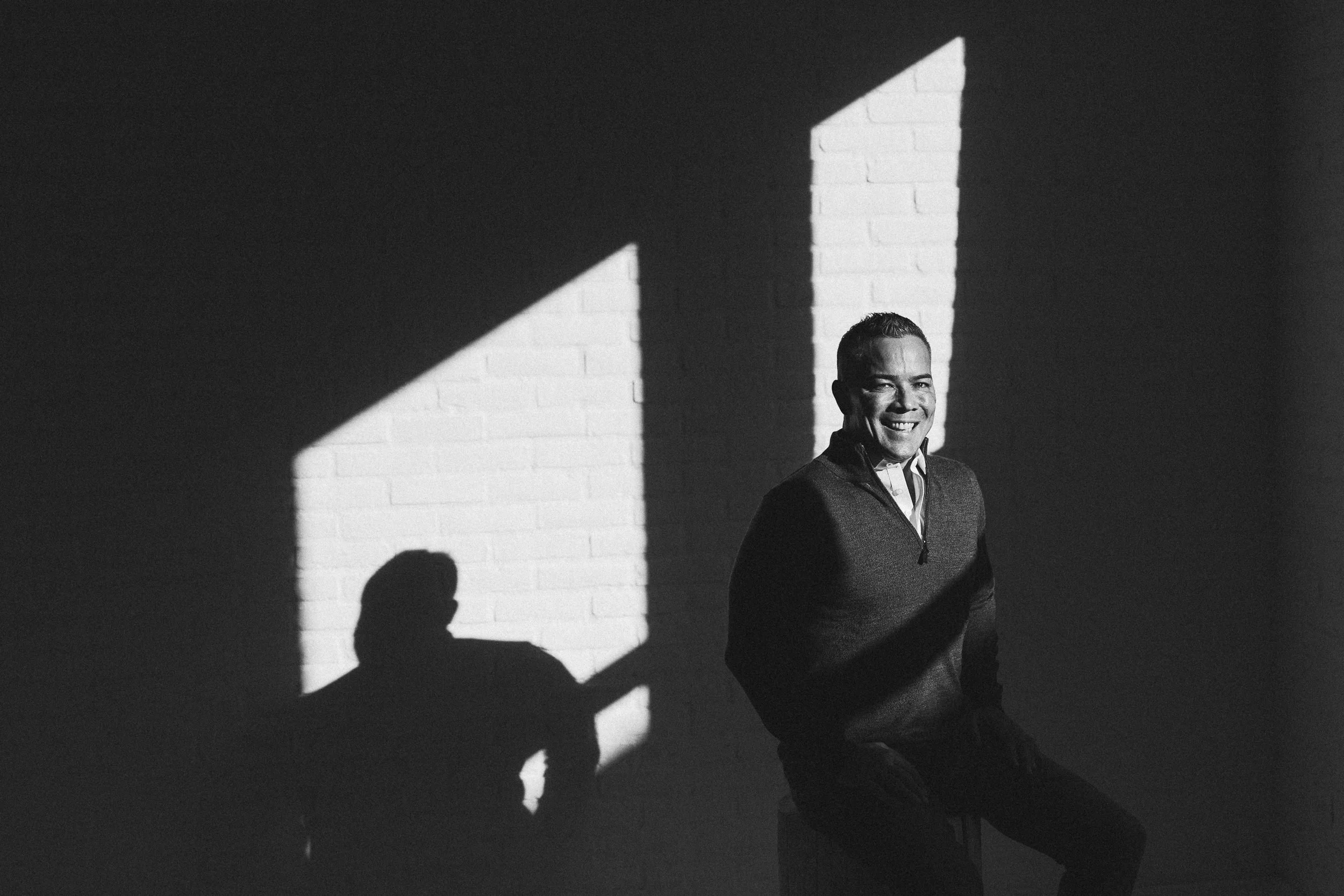 Mortgage broker smiling in natural window light during a branding photography session in a studio in downtown Boise.