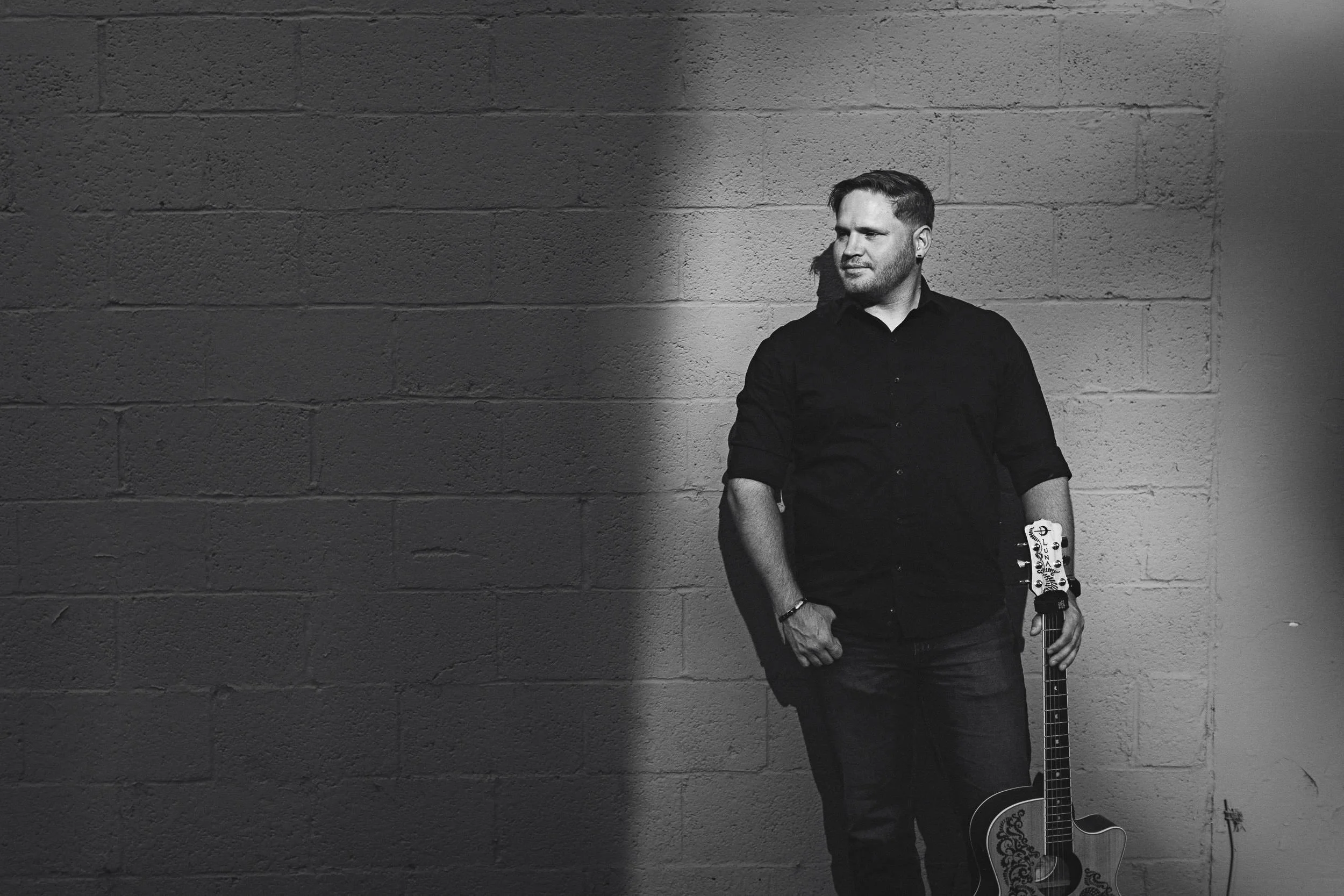 Musician leaning against a brick wall during a branding photography session in downtown Boise.